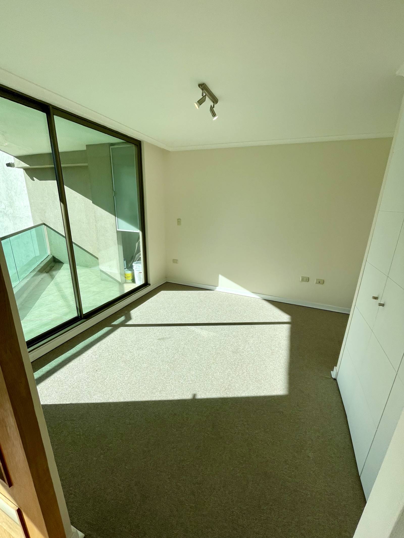Dormitorio alfombrado con ventanal hacia terraza y clóset empotrado
