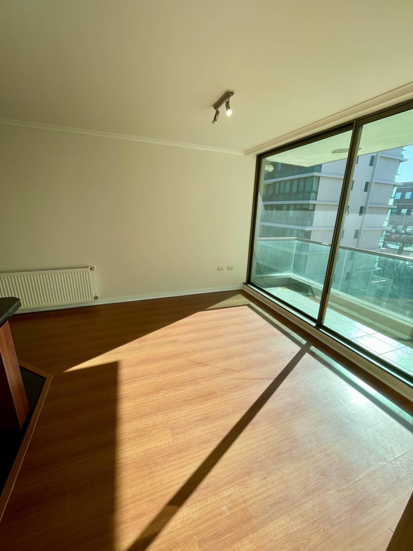 Living con piso flotante, calefactor mural y ventanal