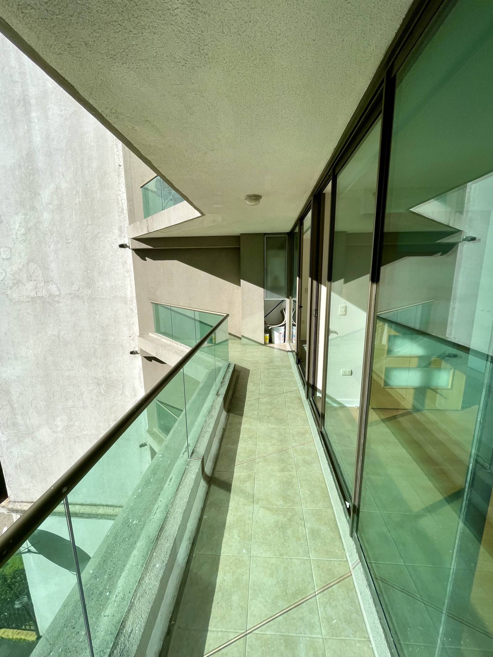 Terraza alargada con baranda de cristal y vista lateral