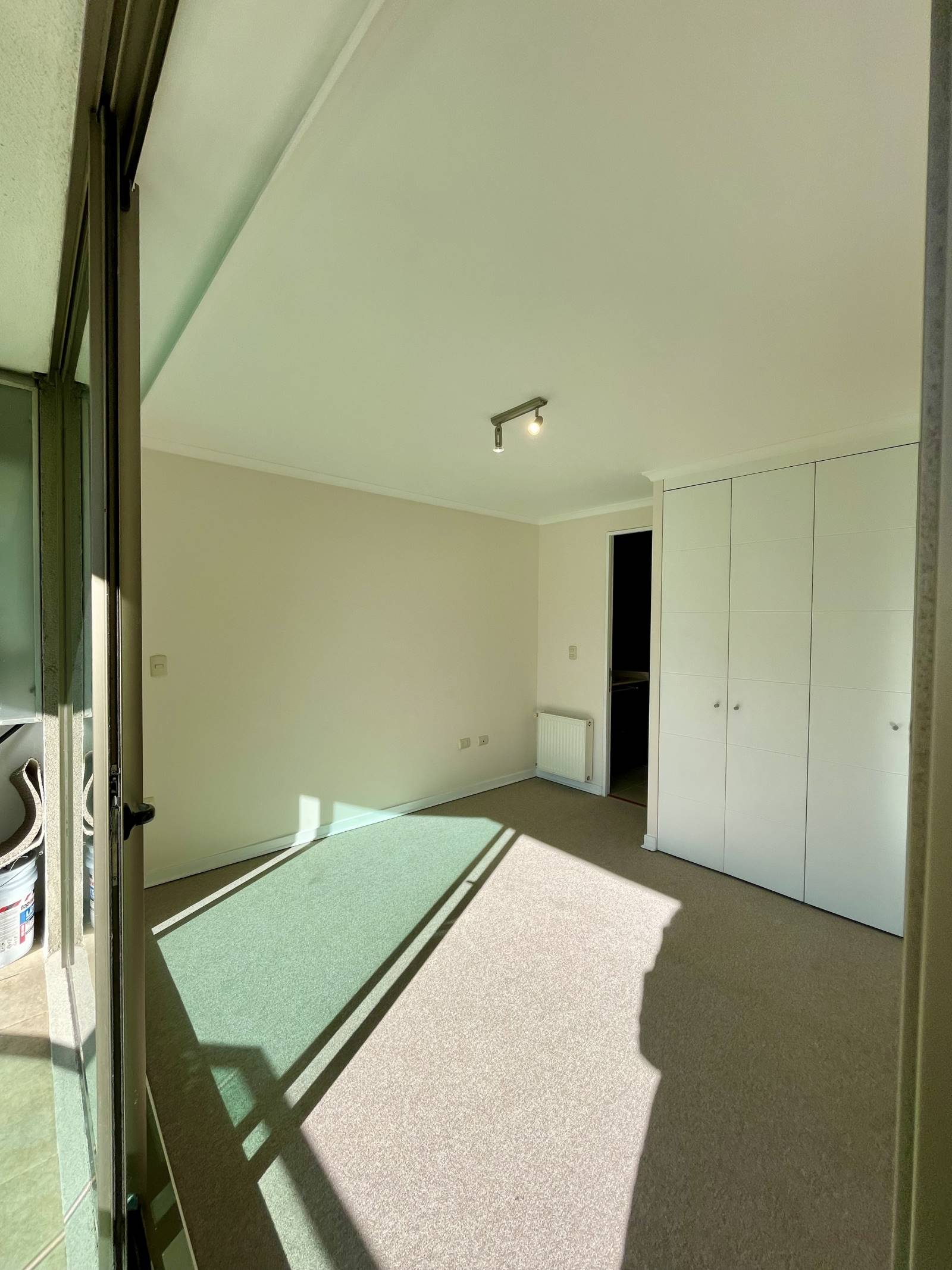 Dormitorio luminoso con alfombra, clóset blanco y calefactor