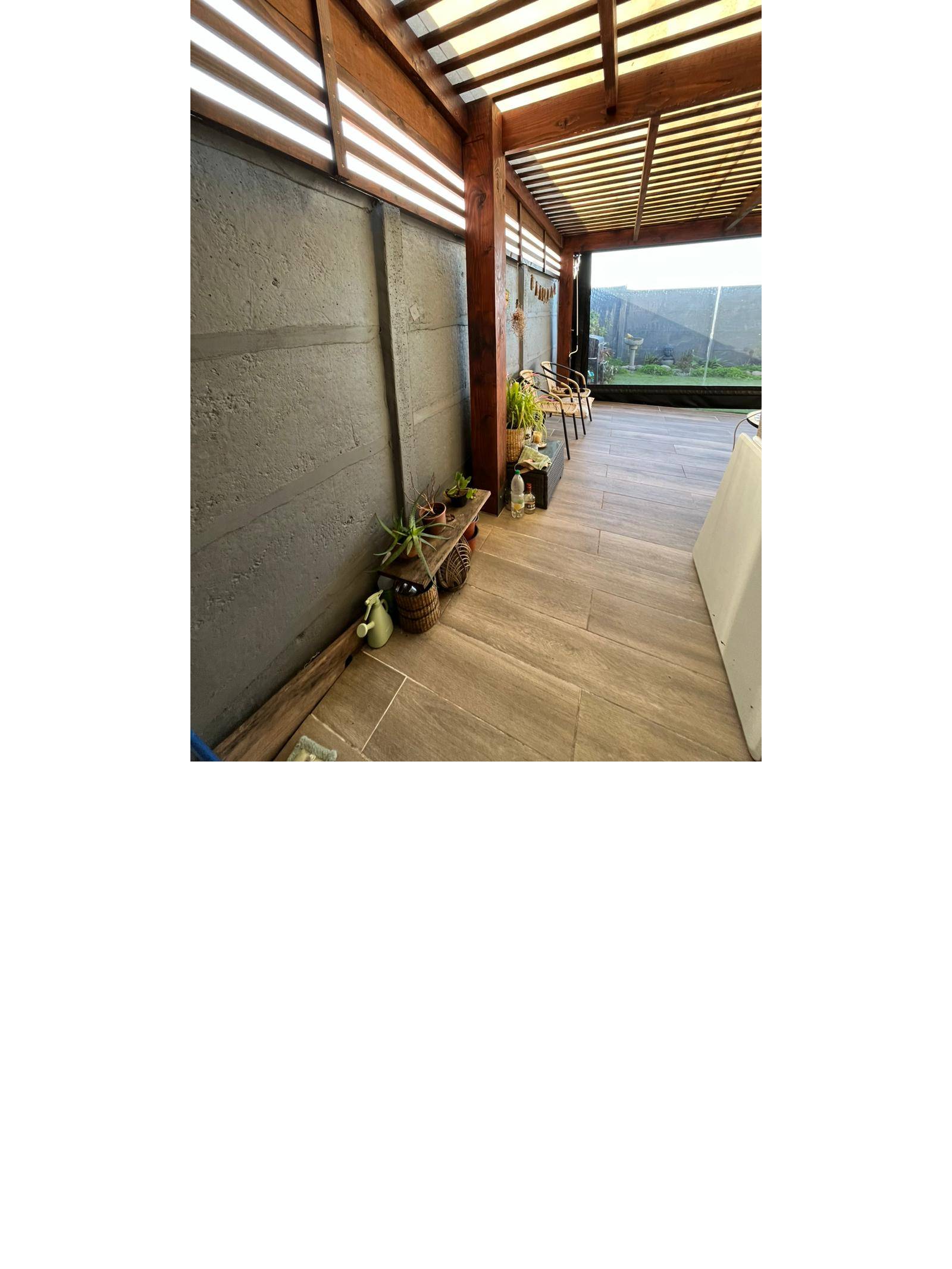 Terraza techada con vigas de madera y plantas decorativas