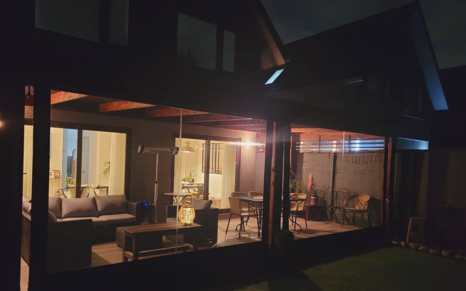 Galería y terraza iluminadas de noche con vista al patio