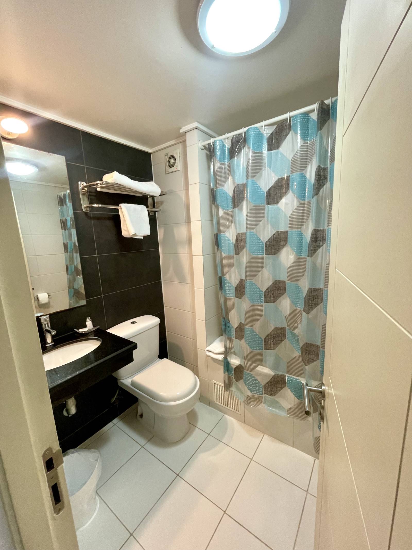 Baño con vanitorio oscuro, inodoro y tina con cortina