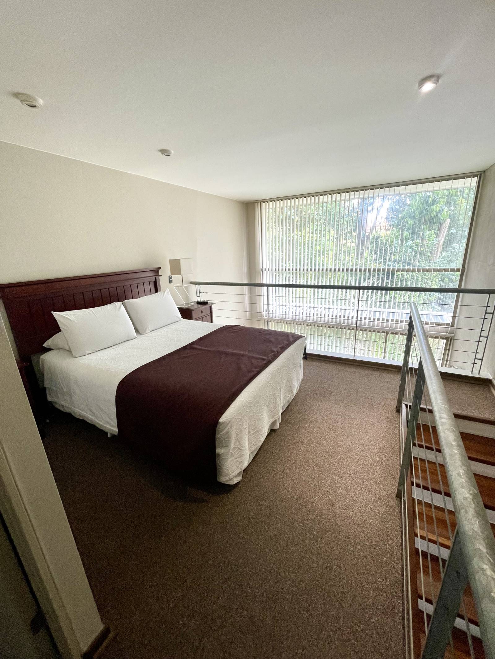 Habitación en mezzanine con cama matrimonial y ventanal amplio