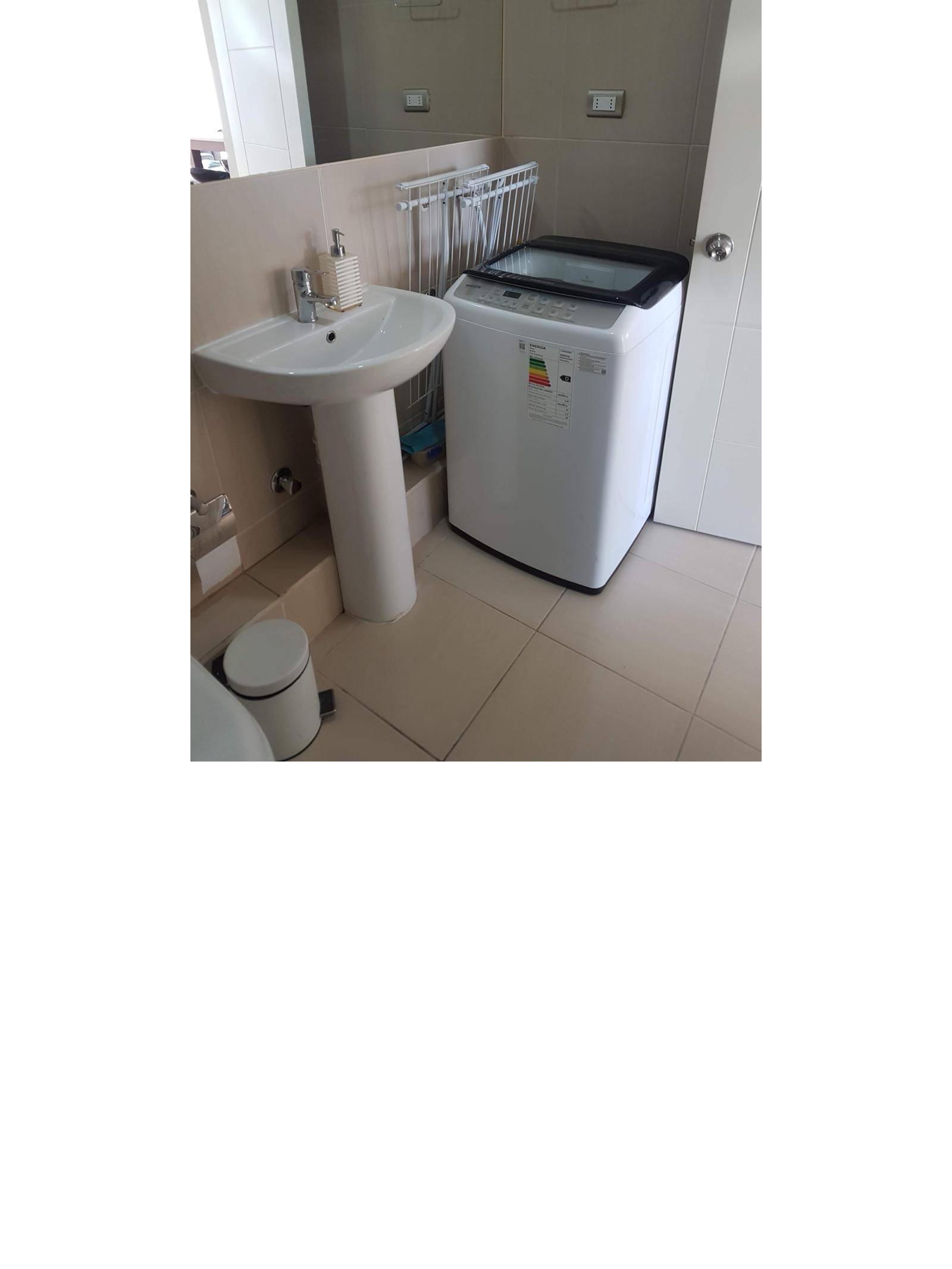 Baño con lavamanos de pedestal y lavadora instalada