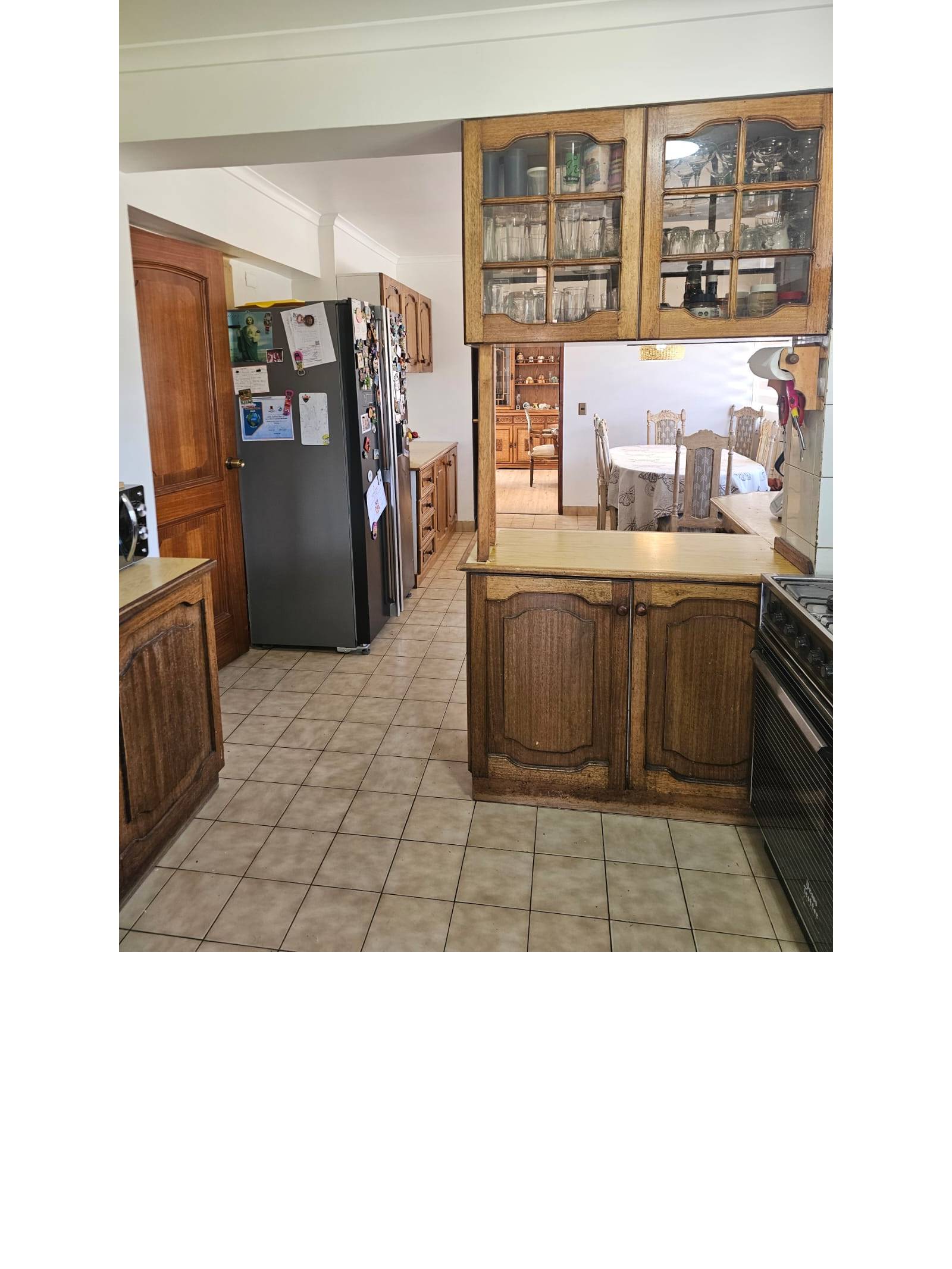 Cocina con muebles superiores vitrina y vista hacia comedor diario