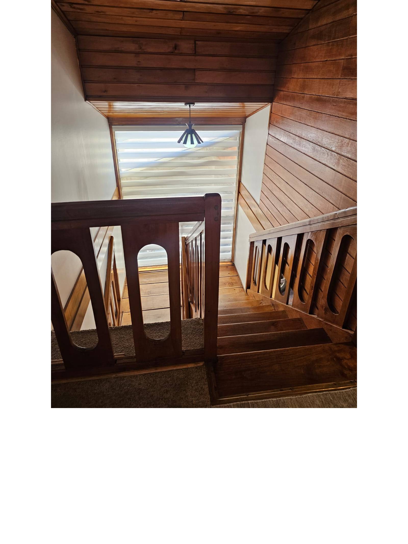Escalera de madera hacia segundo piso con ventana al fondo