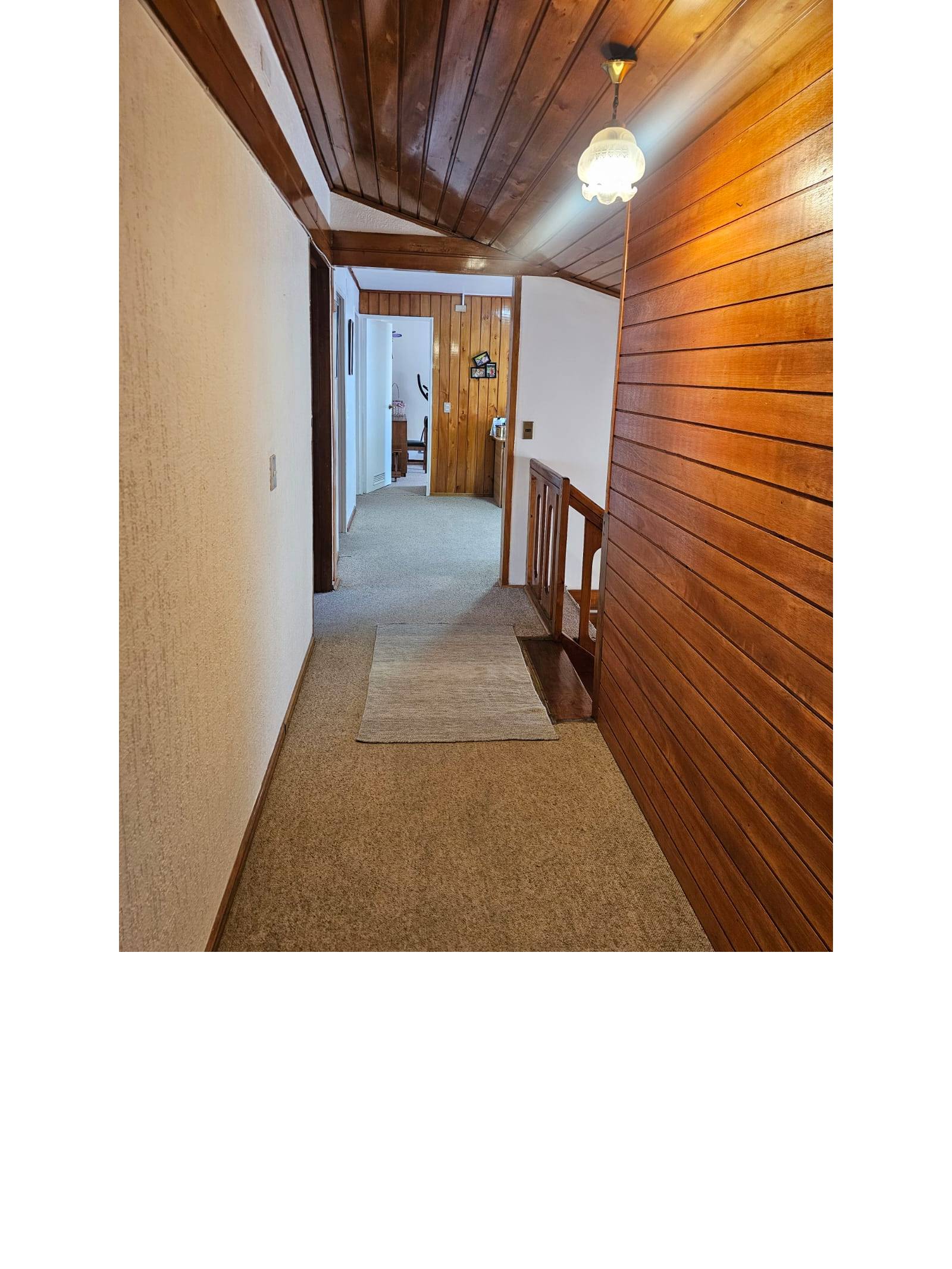 Pasillo de distribución en segundo piso con revestimiento en madera