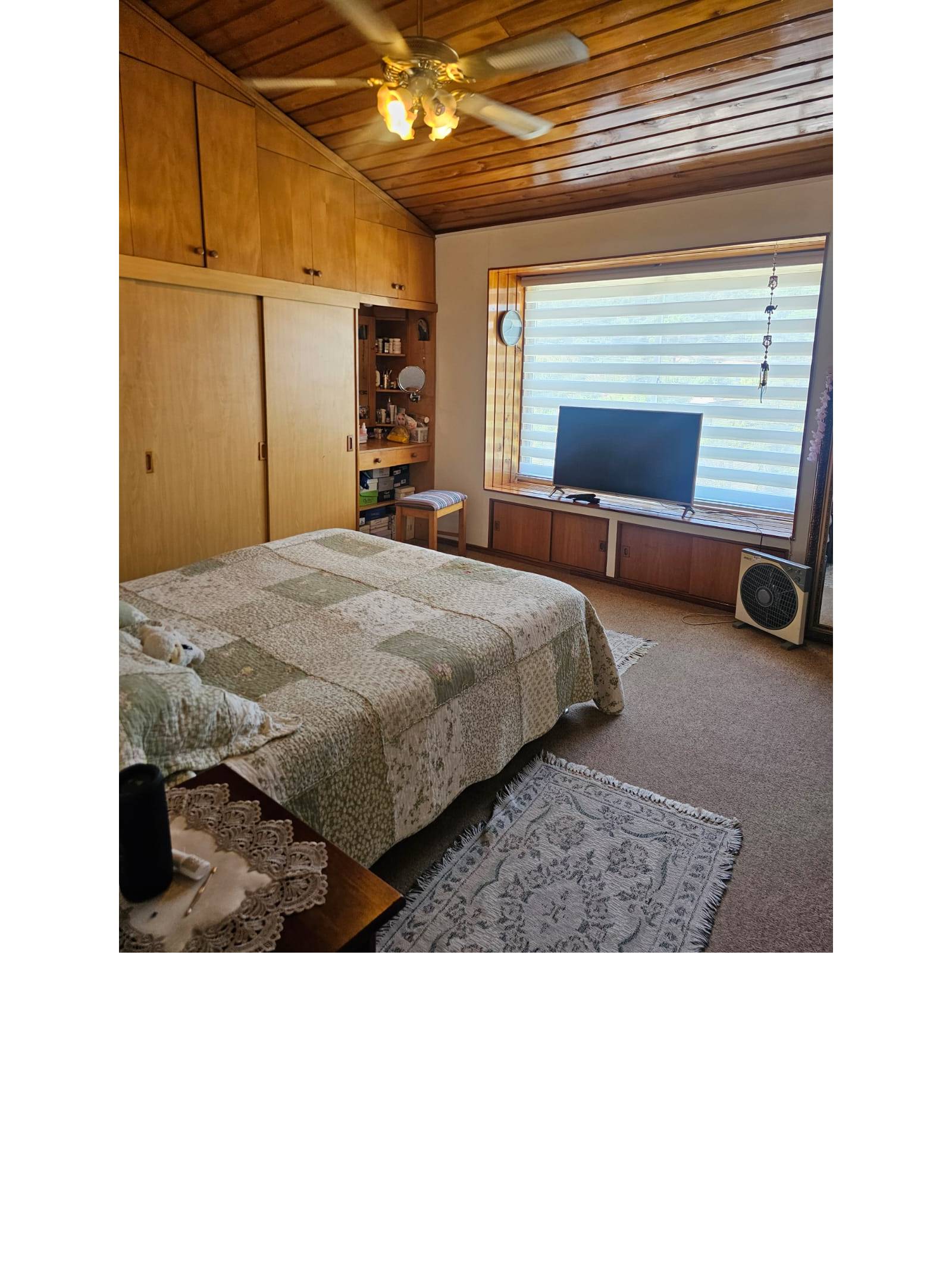 Dormitorio principal con cama matrimonial, closets de madera y televisor