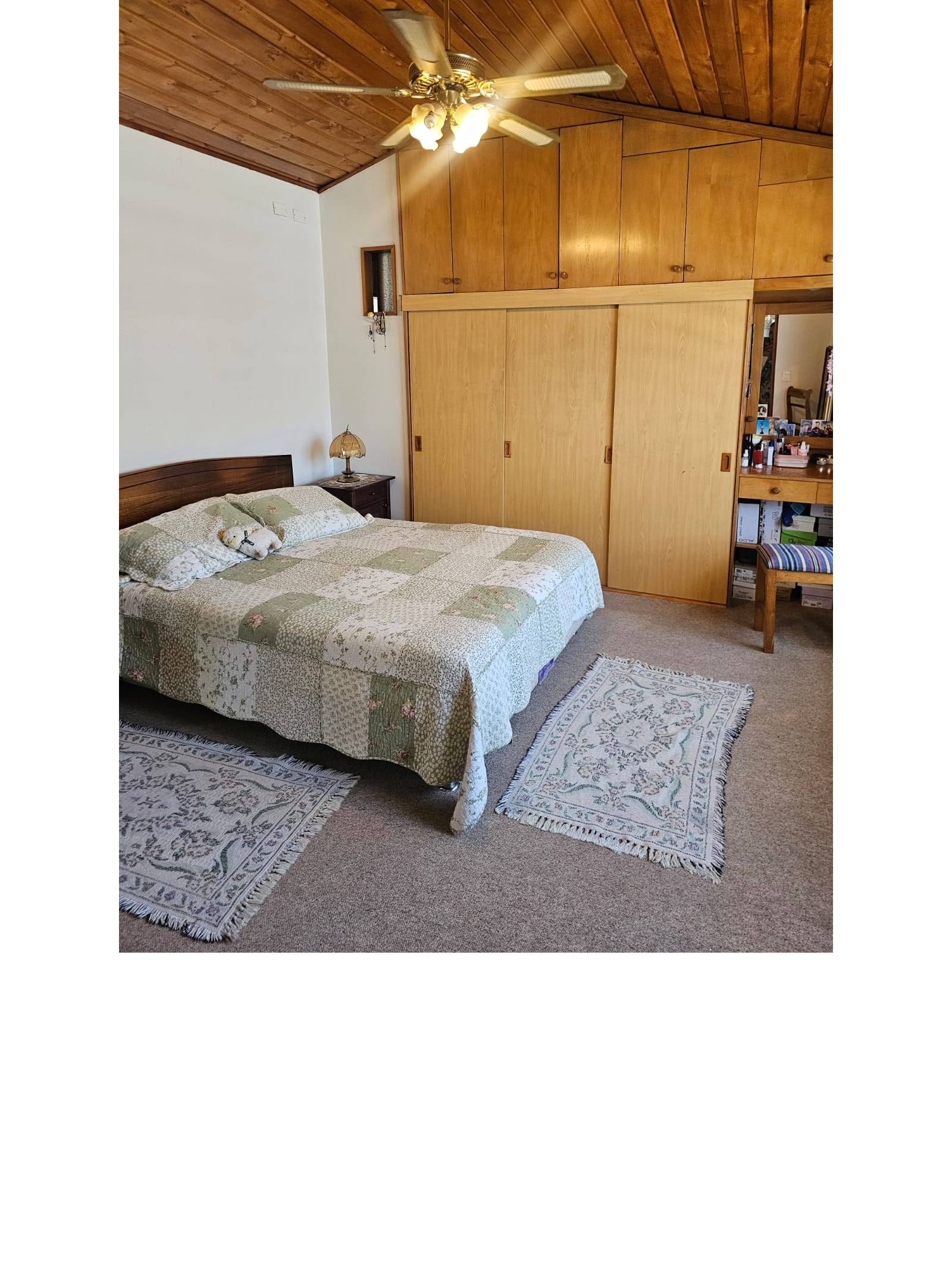Dormitorio matrimonial amplio con closets de madera y ventilador