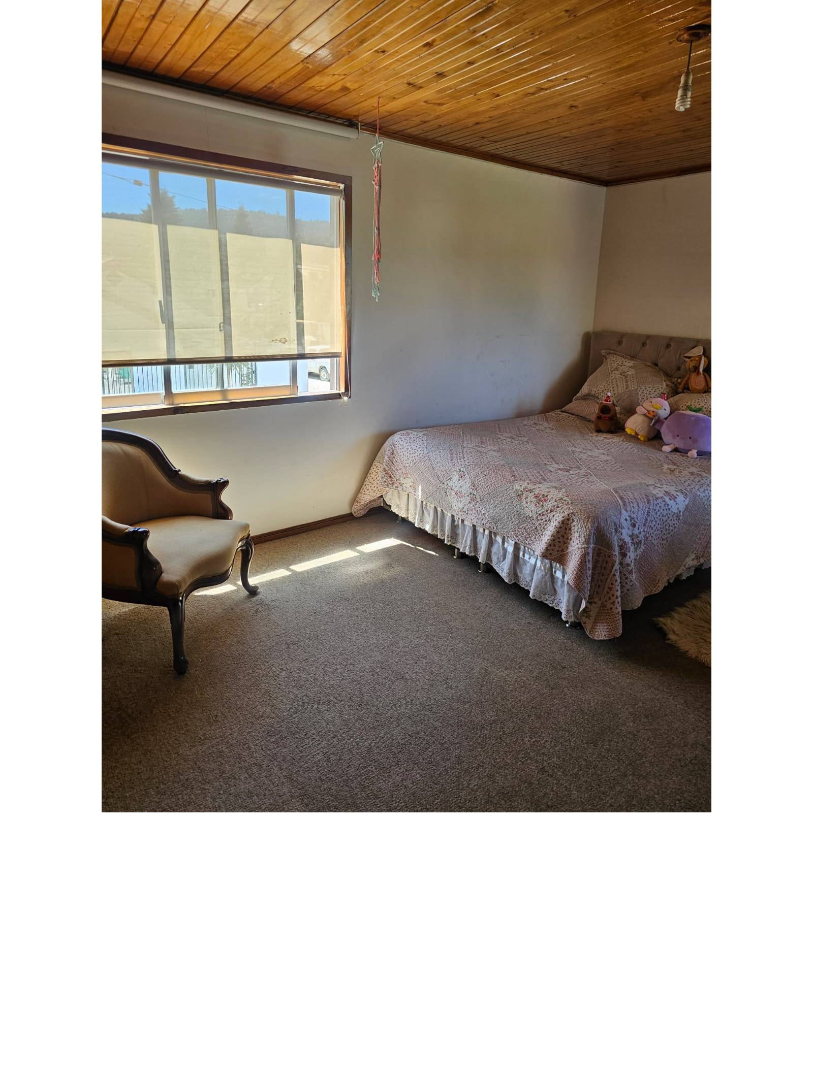 Dormitorio con cama de dos plazas y ventana amplia