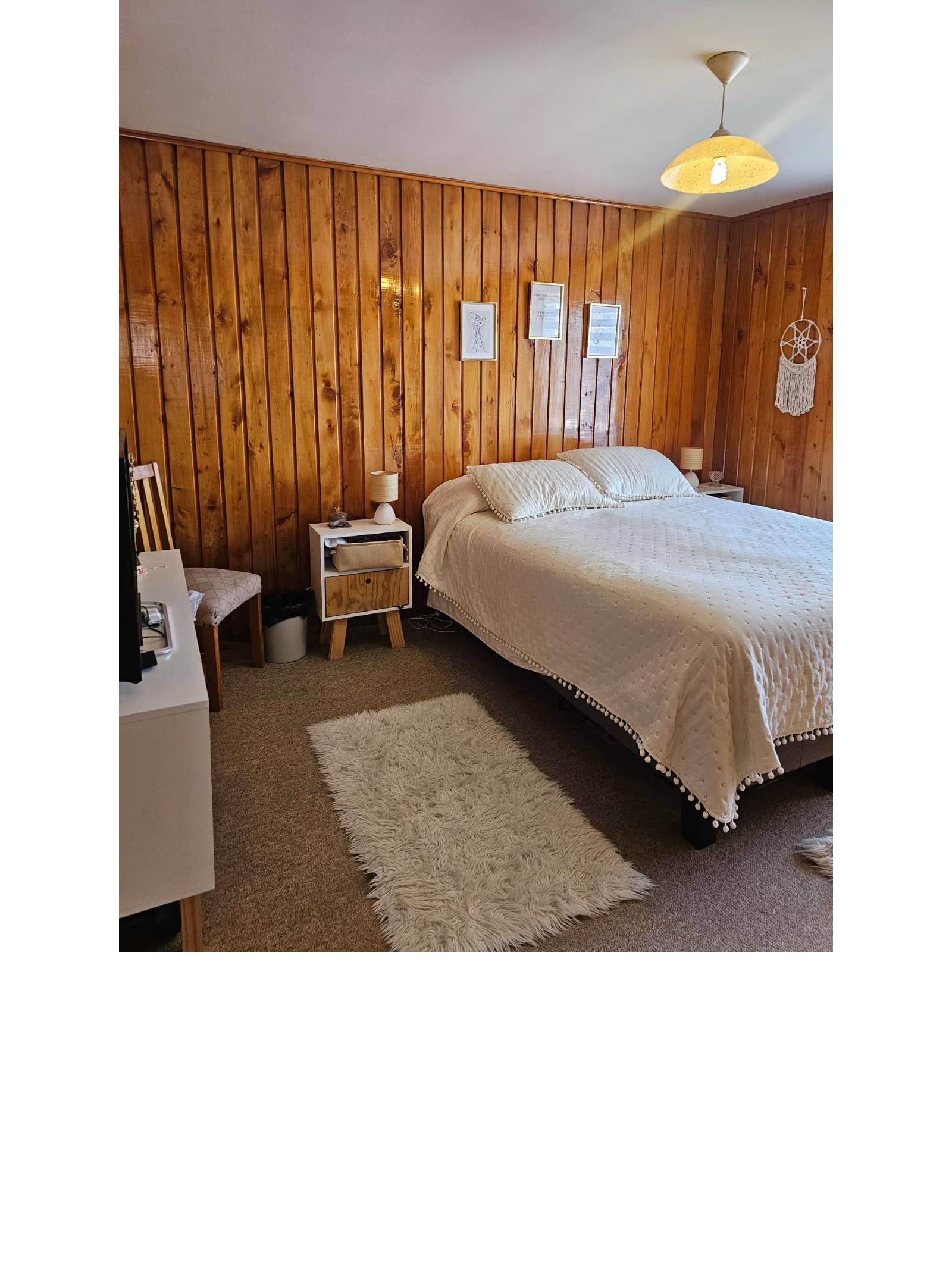 Dormitorio con pared revestida en madera y cama matrimonial