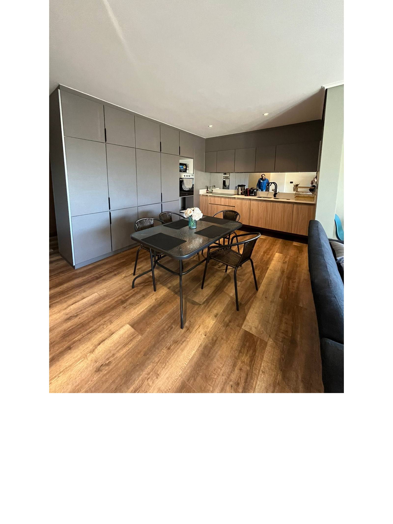 Mesa de comedor frente a cocina americana con muebles grises