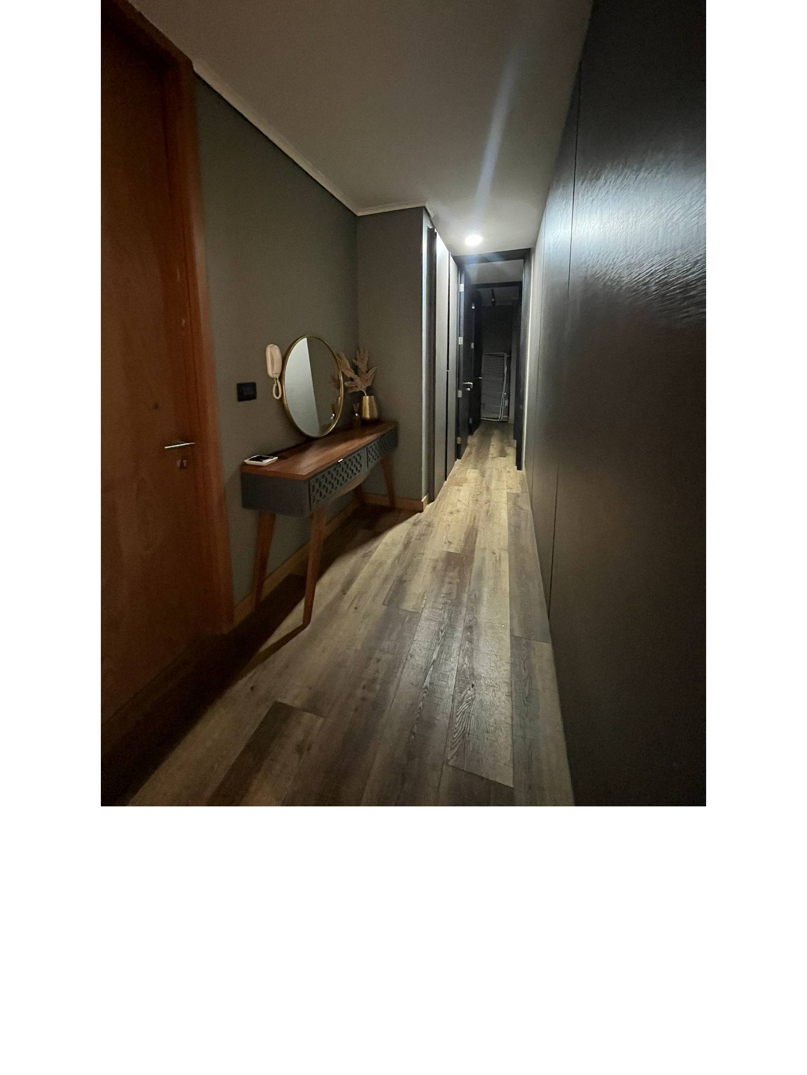 Pasillo de distribución con arrimo de madera y espejo circular