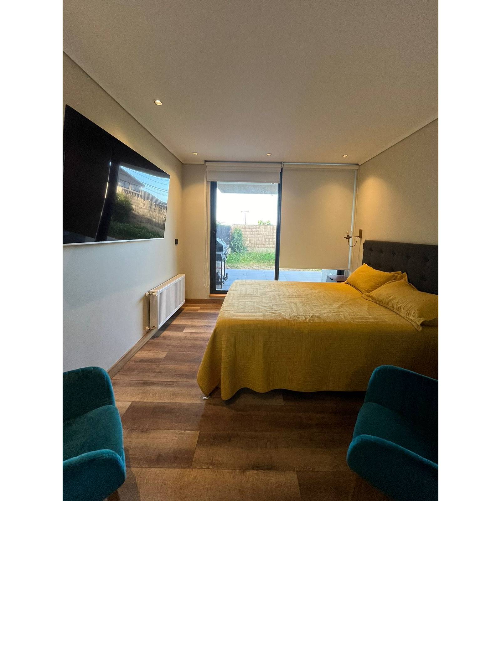 Dormitorio principal con cama matrimonial y ventanal con persianas