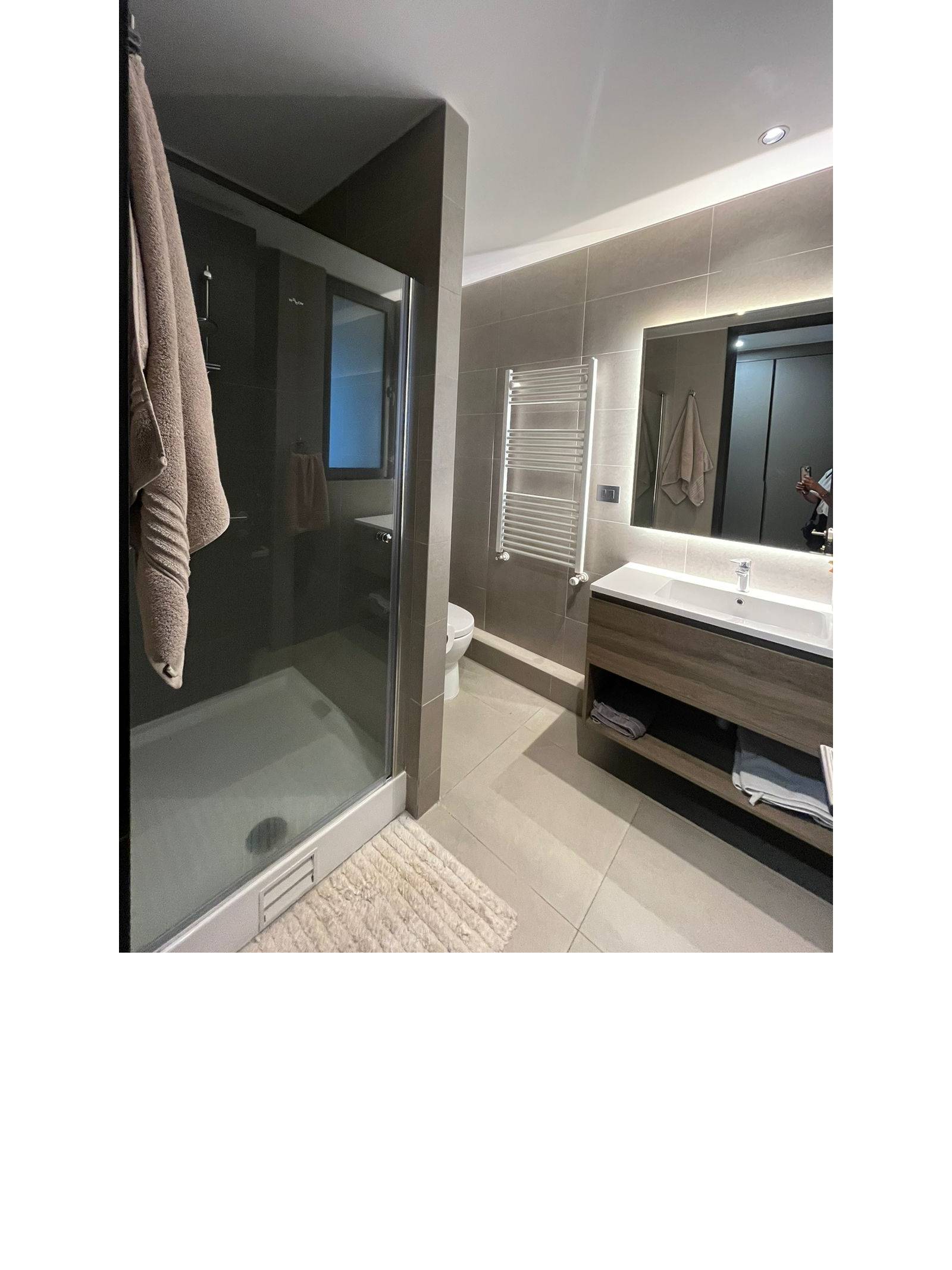 Baño moderno con vanitorio de madera y mampara de ducha