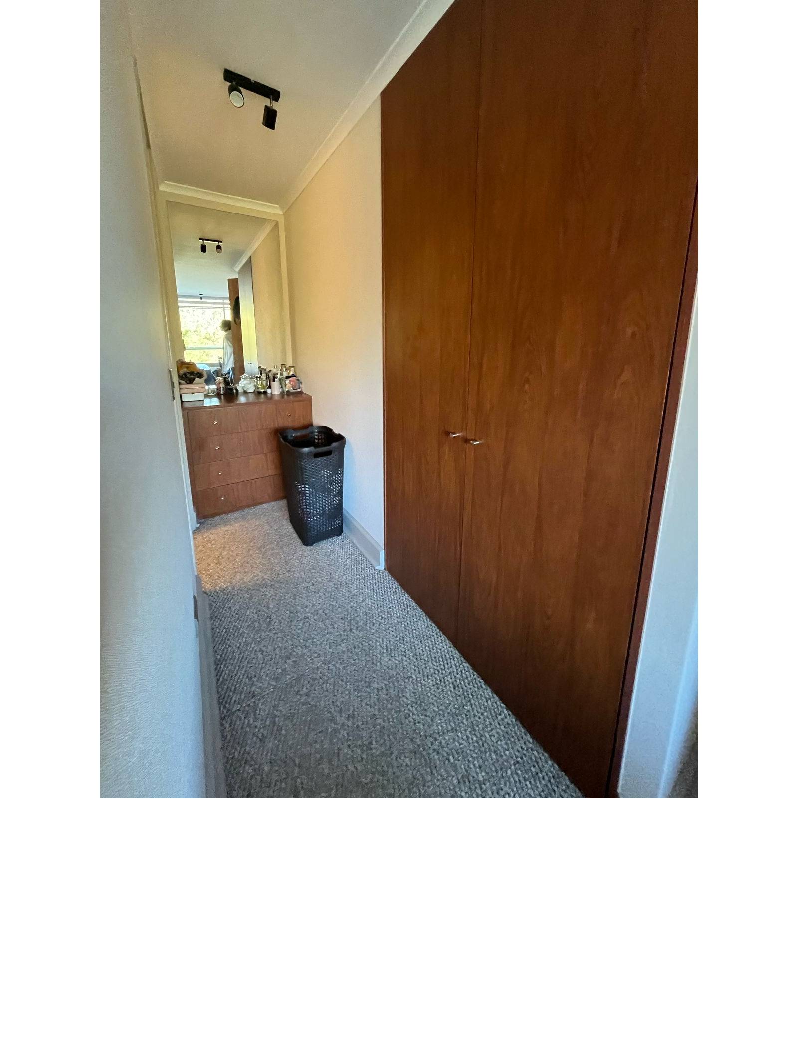 Pasillo hacia dormitorio con clóset de madera empotrado.