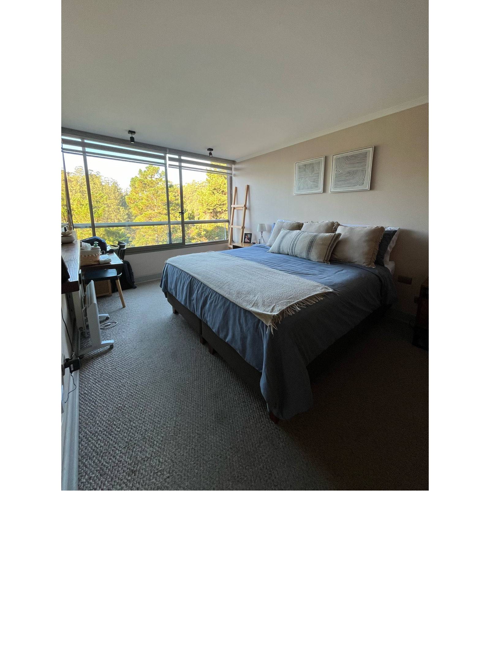 Dormitorio principal con cama matrimonial y ventanal con vista arbolada.