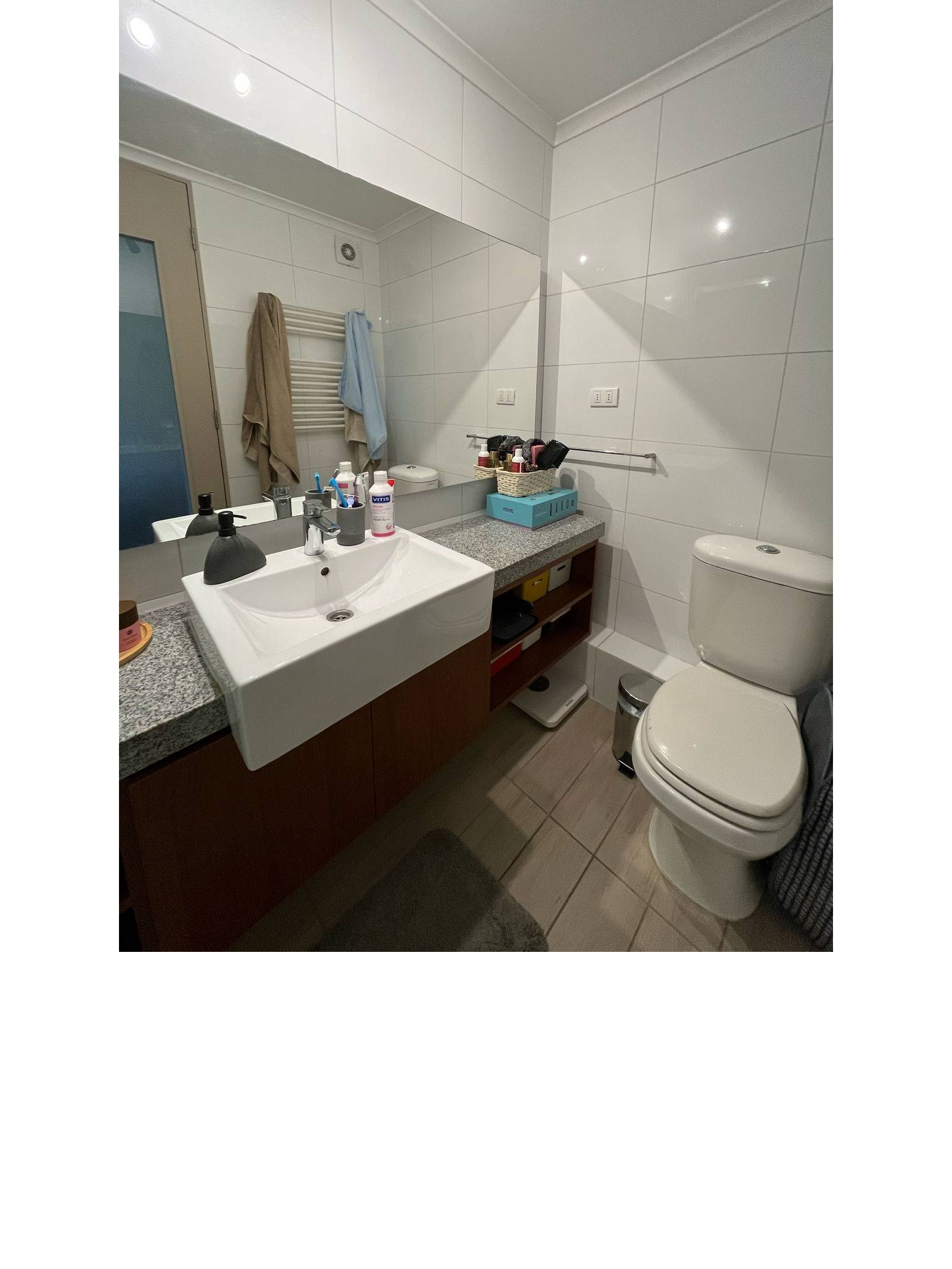 Baño con lavamanos moderno, cubierta de granito, inodoro y espejo.