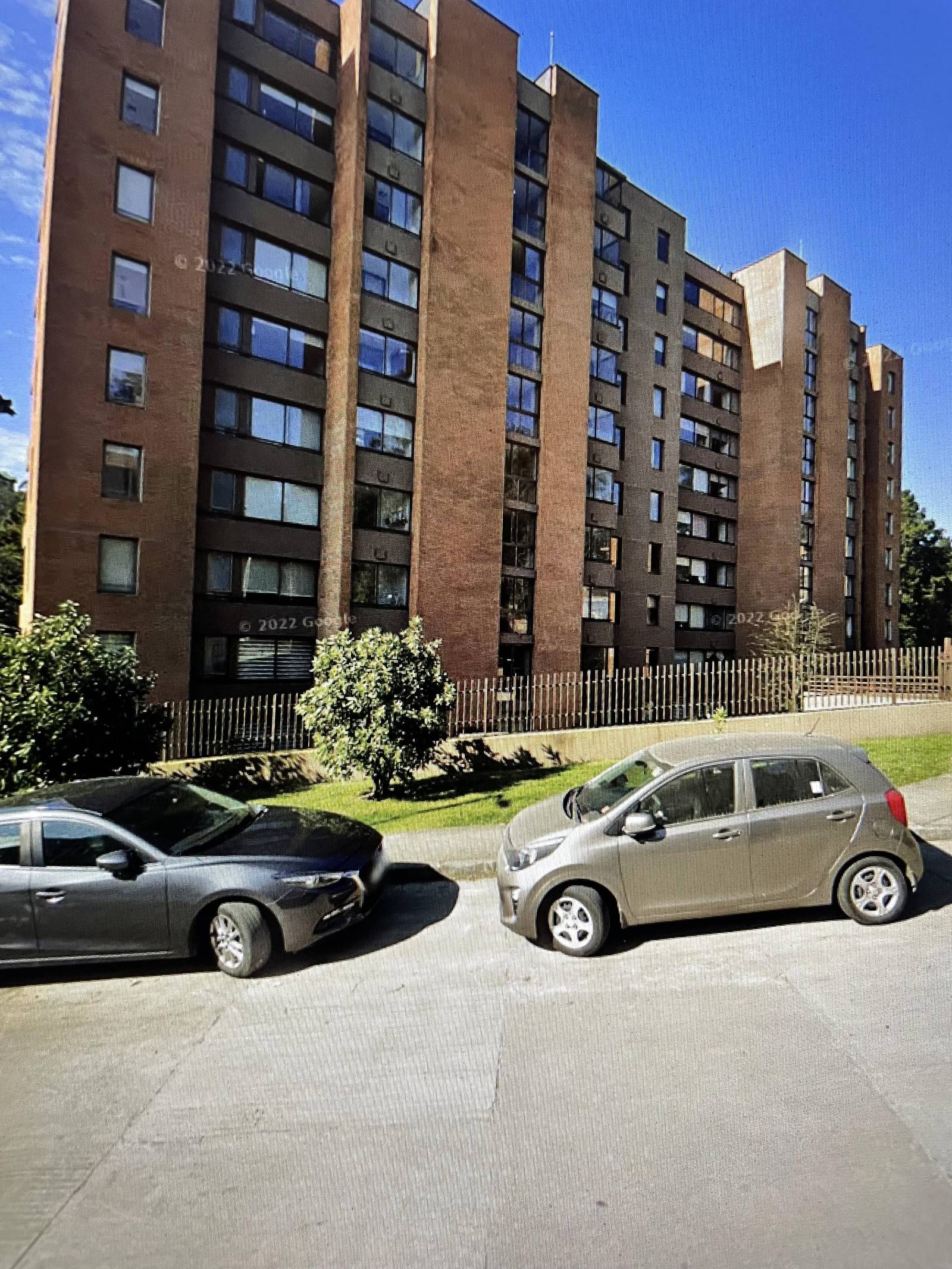 Edificio residencial de ladrillo visto con reja perimetral exterior.