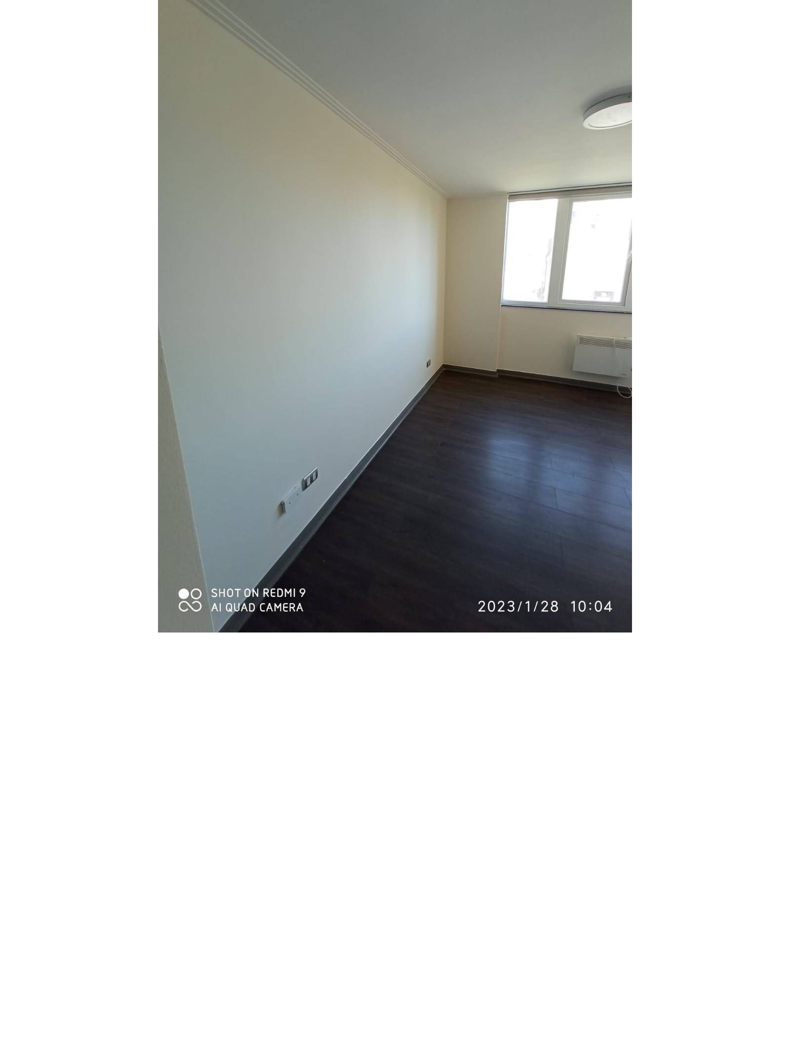 Estar vacío con piso flotante oscuro y ventana luminosa