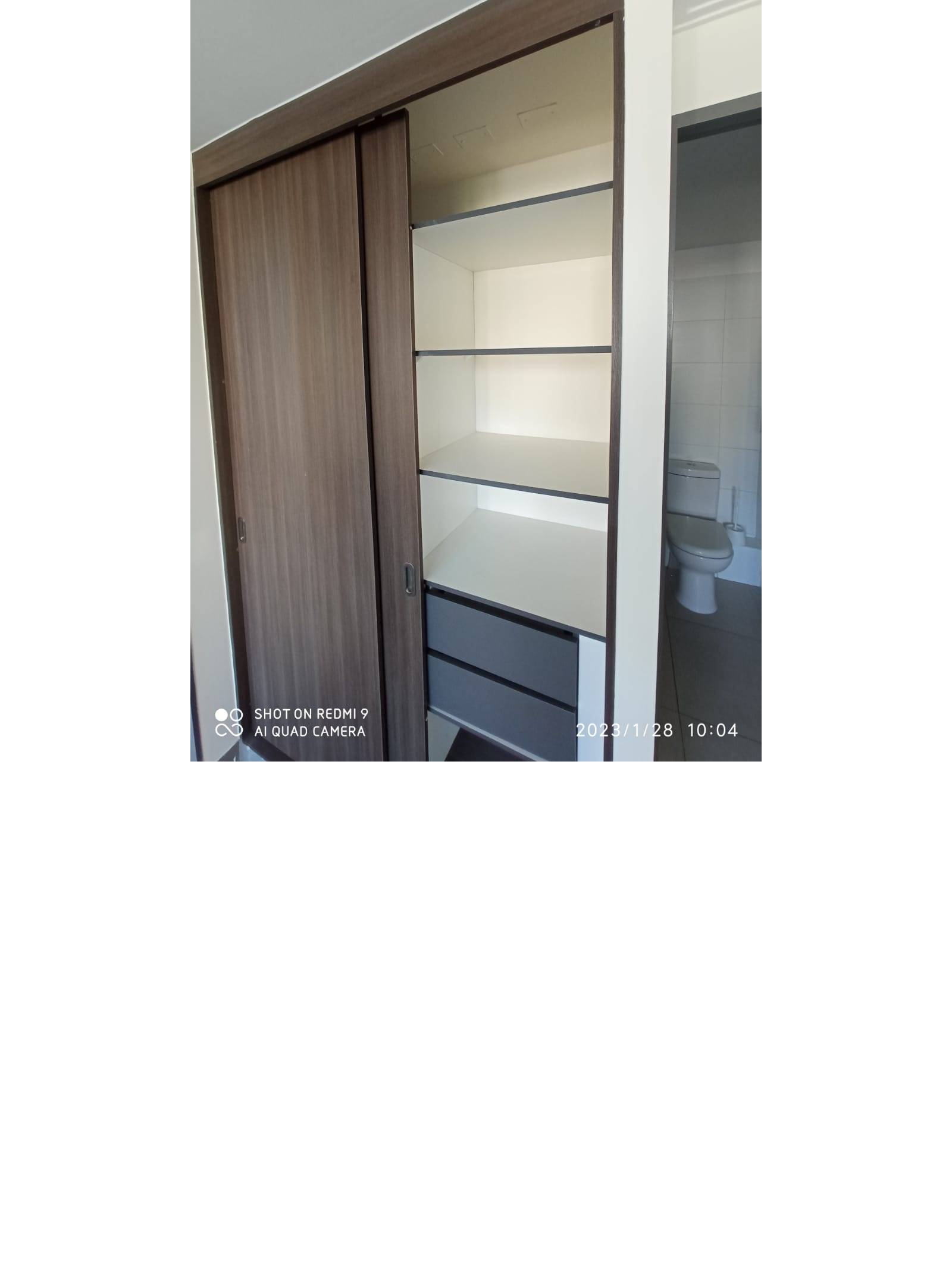 Clóset empotrado con repisas y vista hacia el baño en suite