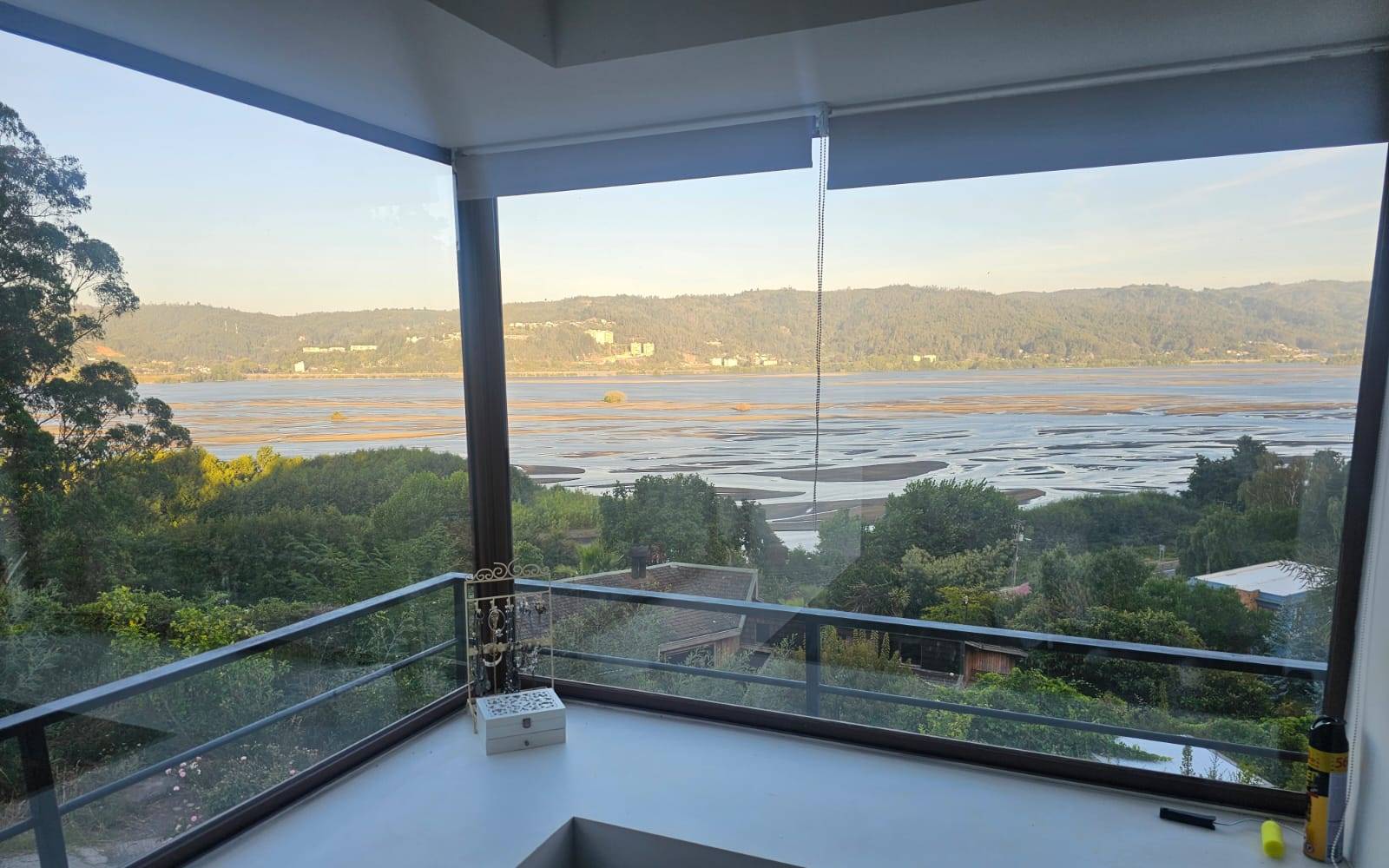 Balcón con baranda de vidrio y vista al río.