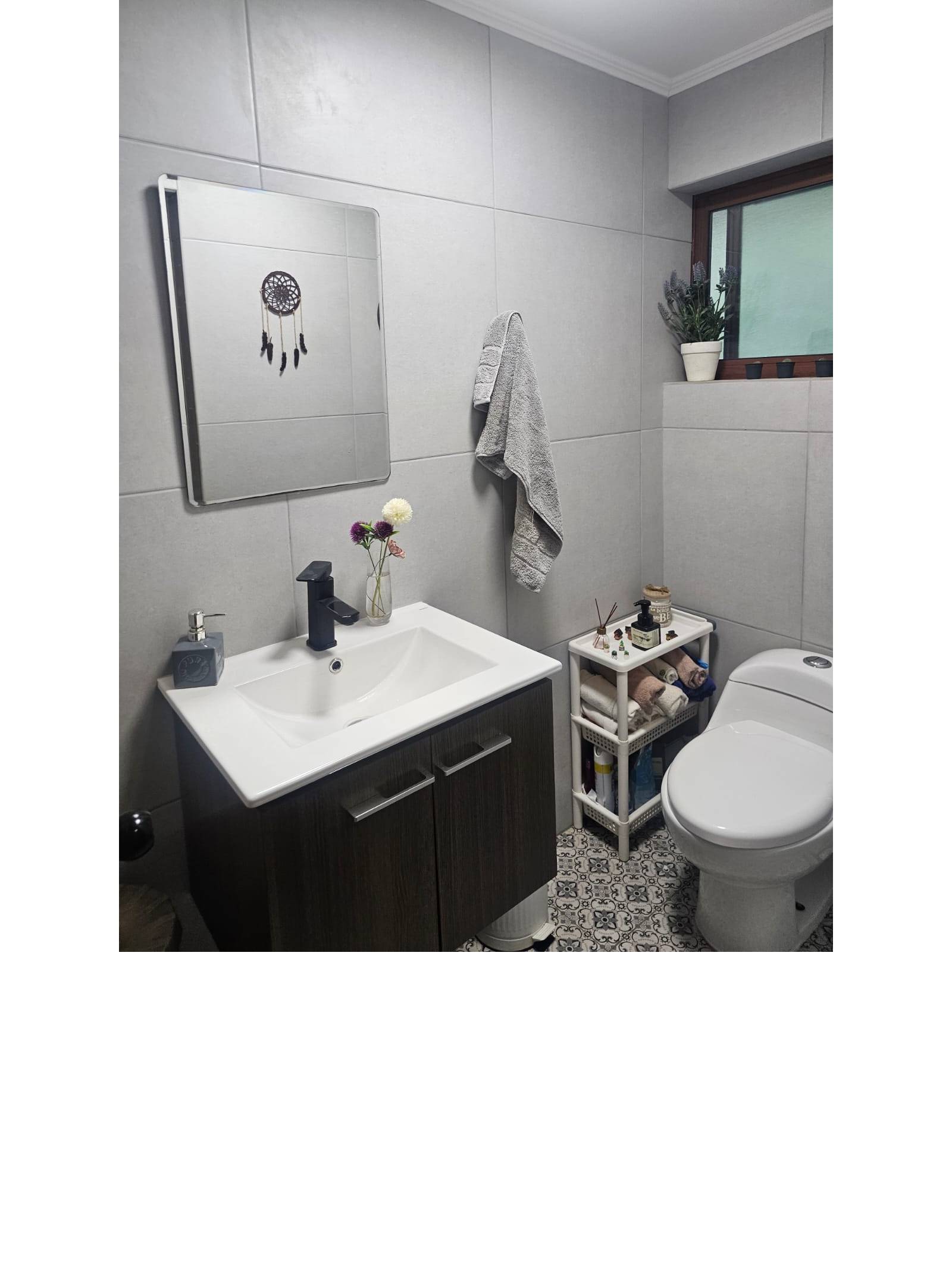 Baño con vanitorio moderno, espejo y paredes revestidas.