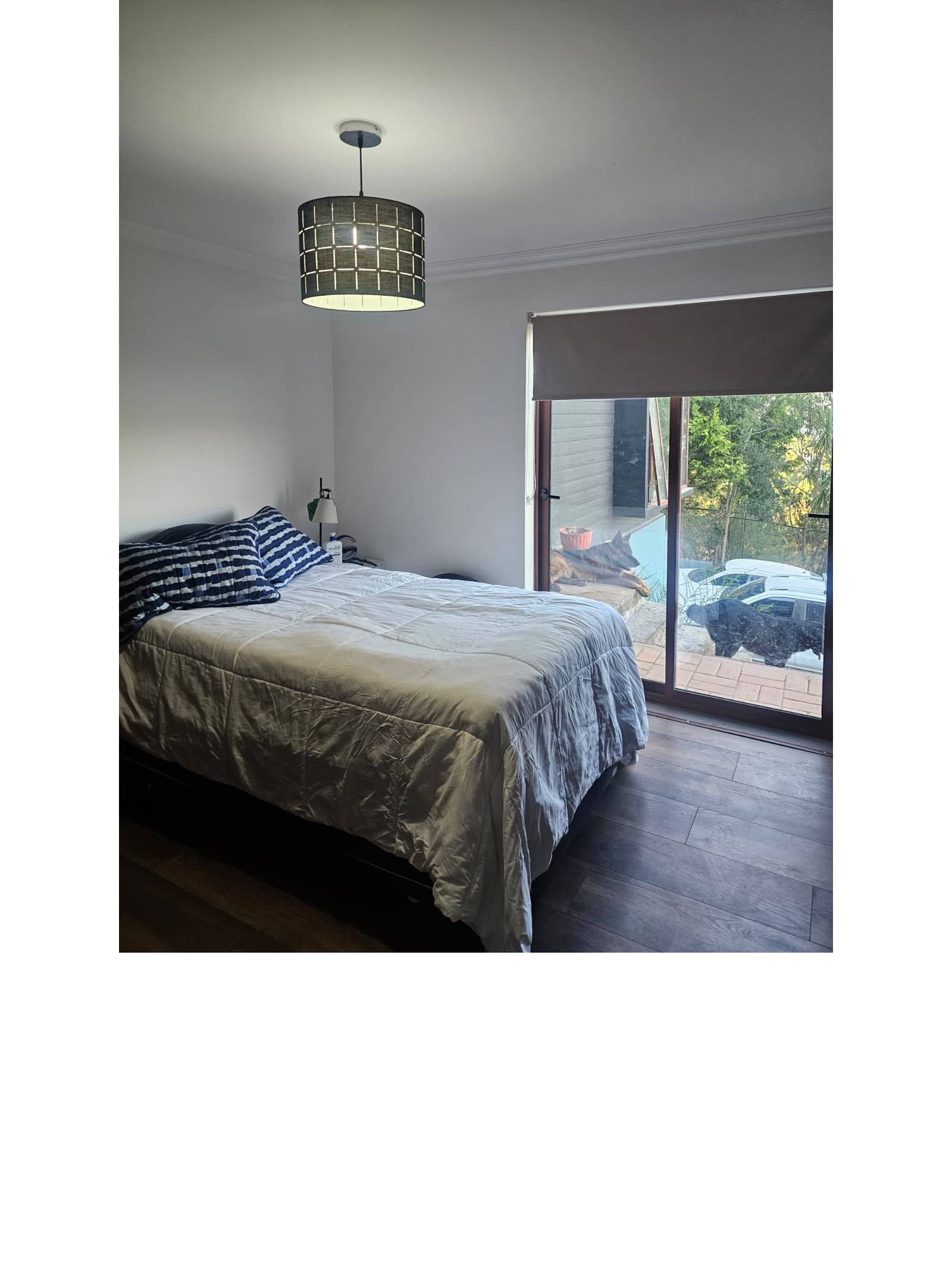 Dormitorio secundario con cama y salida a patio exterior.