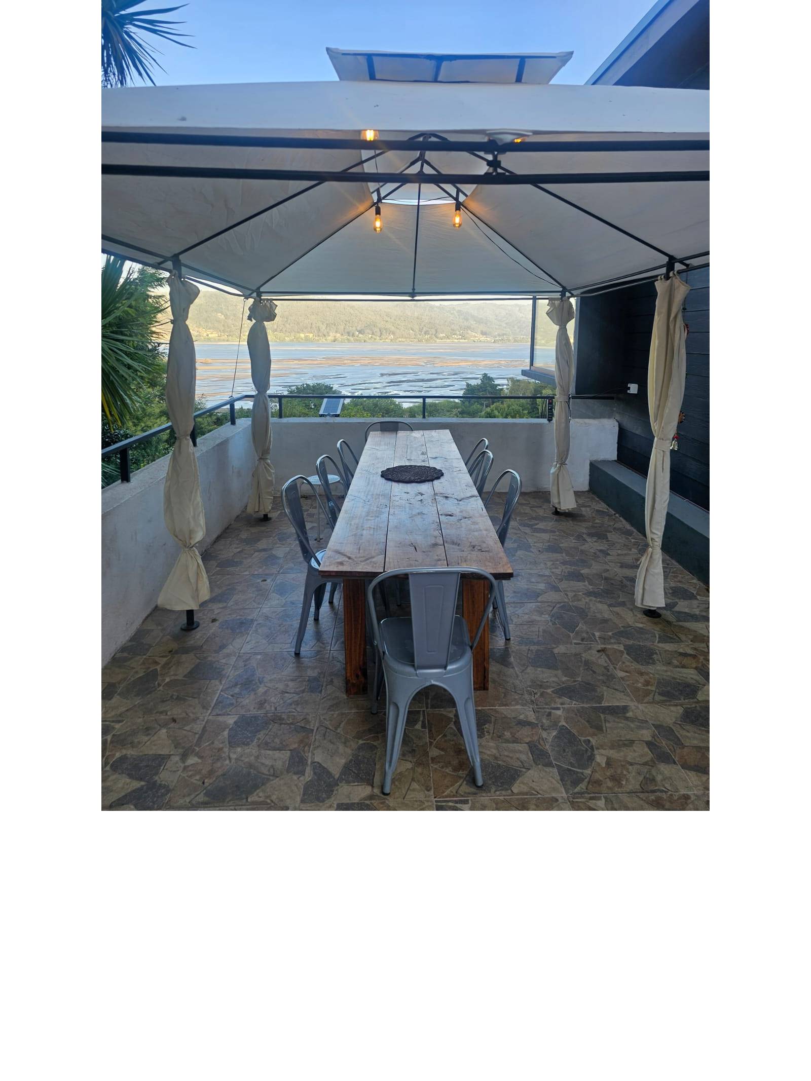 Terraza con comedor exterior bajo toldo y vista despejada.