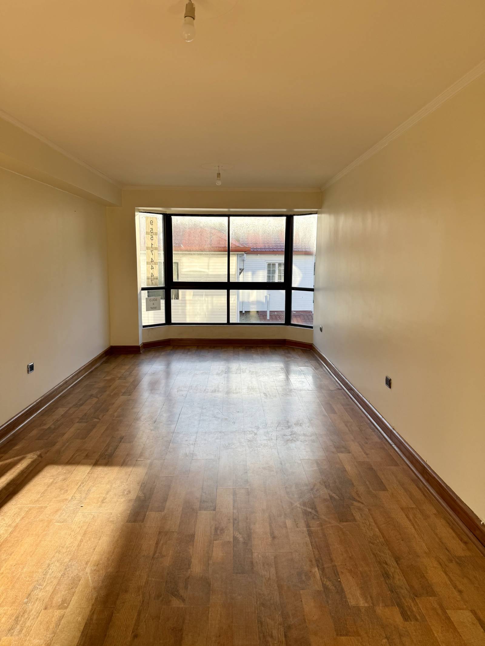 Living amplio con piso flotante y ventanal bow window
