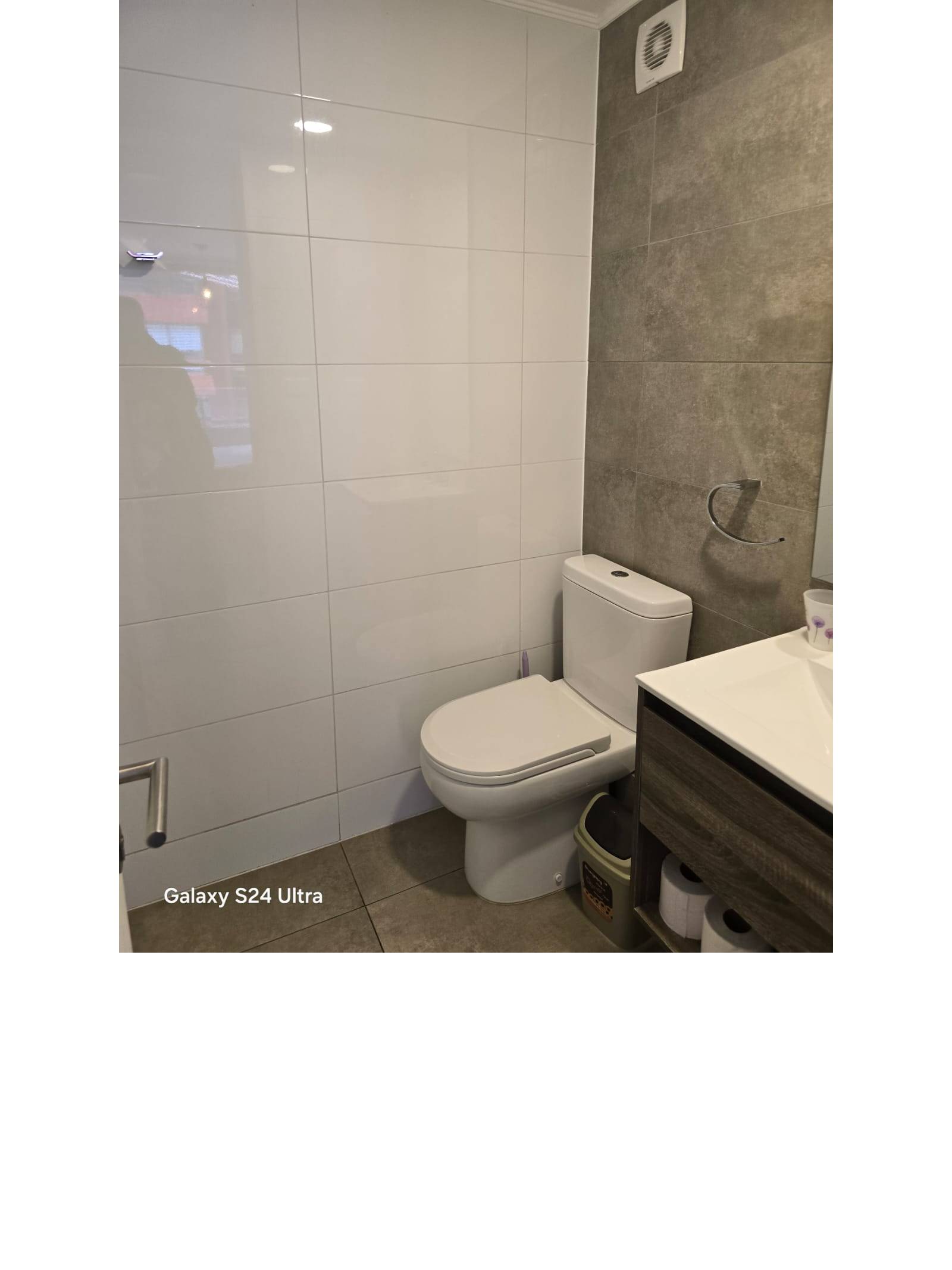 Baño con vanitorio moderno y sanitarios en cerámica blanca