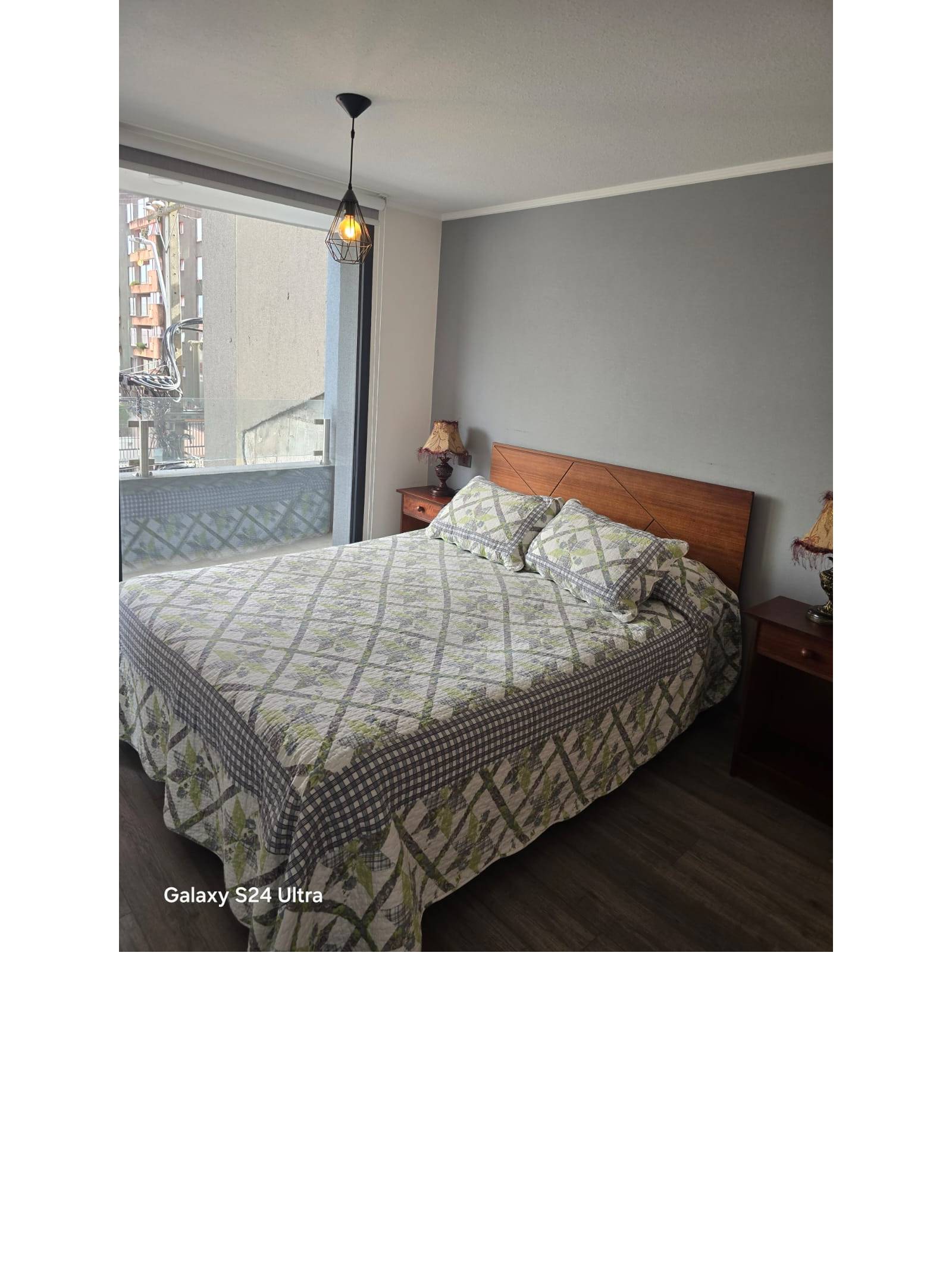 Dormitorio con cama matrimonial, respaldar de madera y luminaria