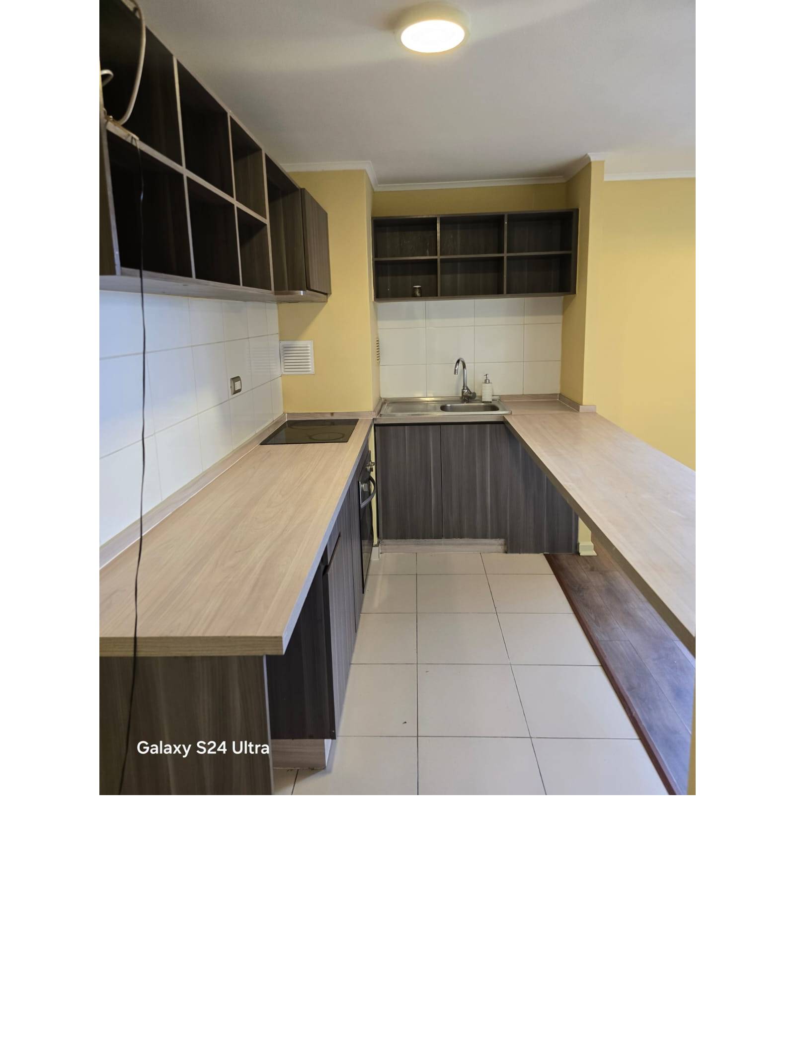 Cocina integrada con mesón desayunador y muebles oscuros