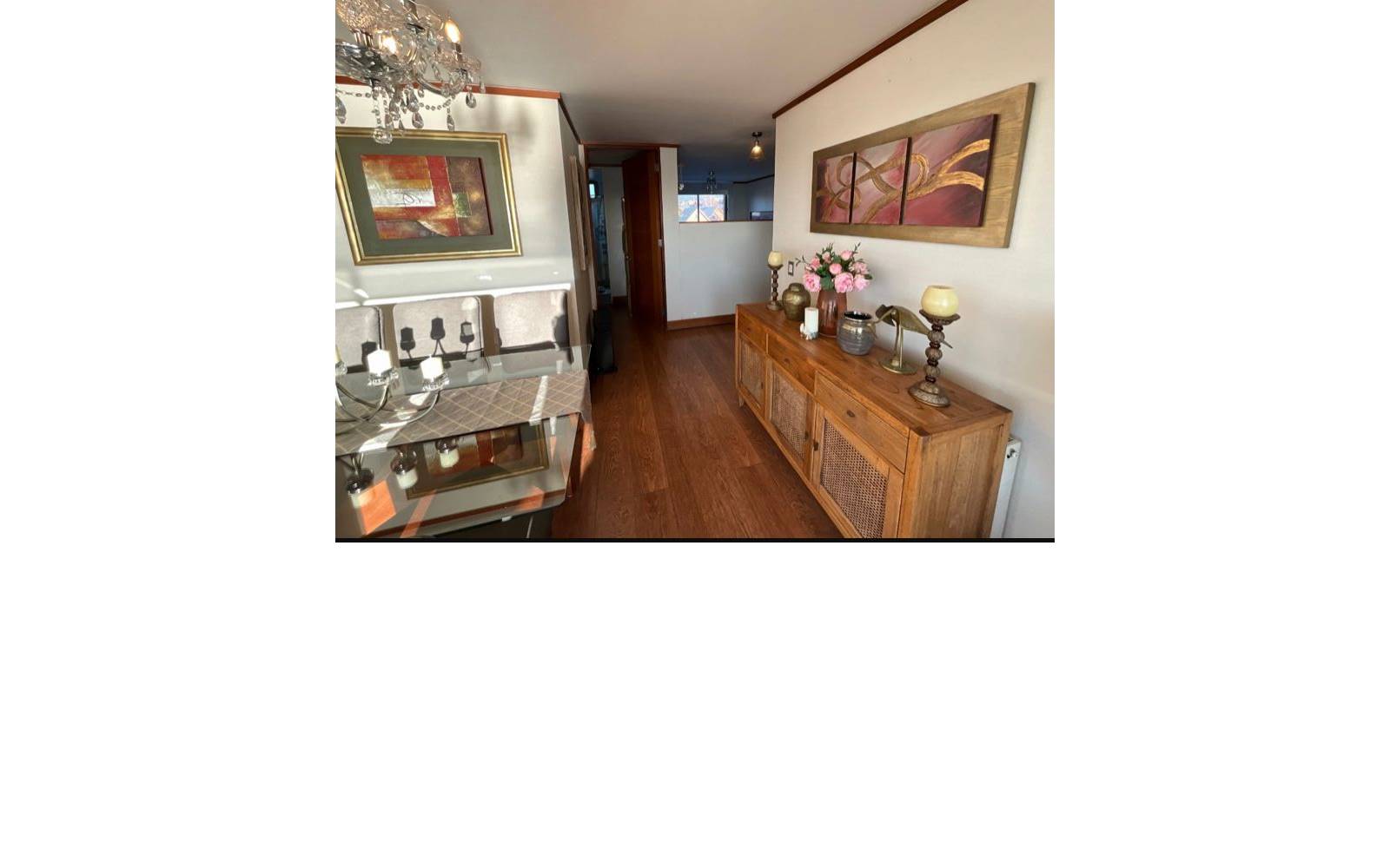 Hall de acceso interior con mueble de madera y cuadros decorativos