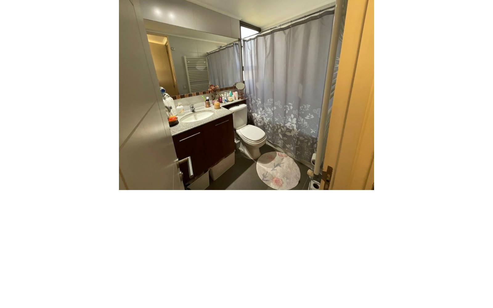 Baño con vanitorio oscuro, espejo grande y tina con cortina