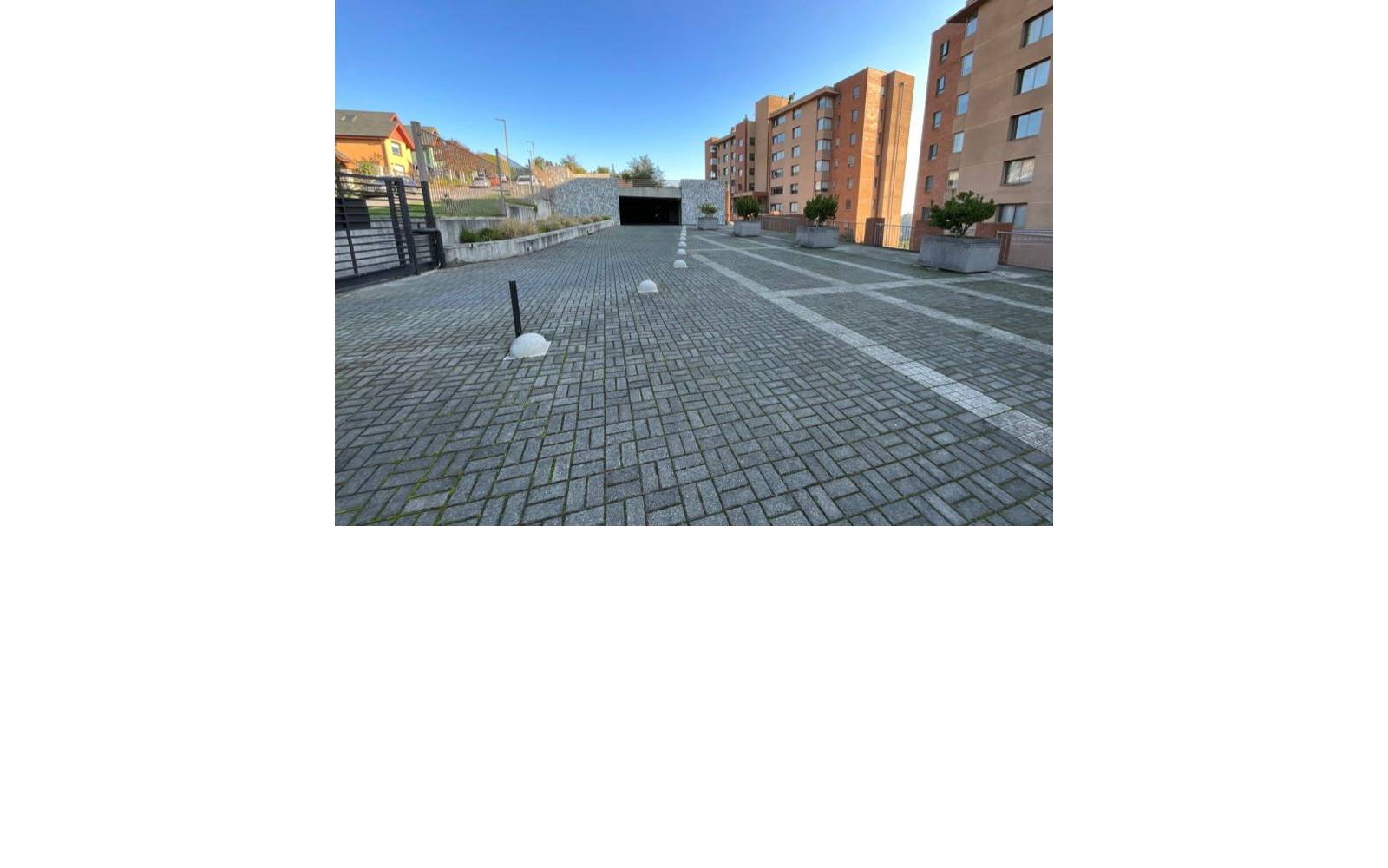 Patio exterior adoquinado y acceso vehicular al estacionamiento