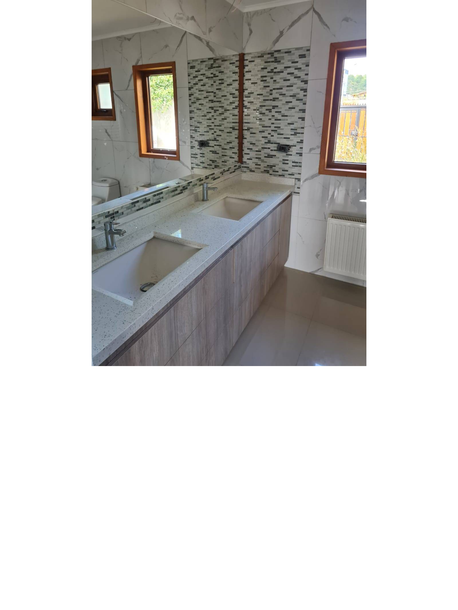 Baño con vanitorio doble, grifería moderna y espejo amplio.