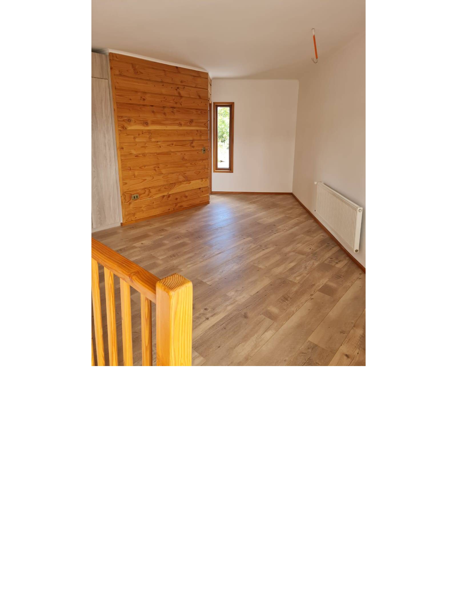 Dormitorio con piso flotante, pared de madera y calefactor mural.