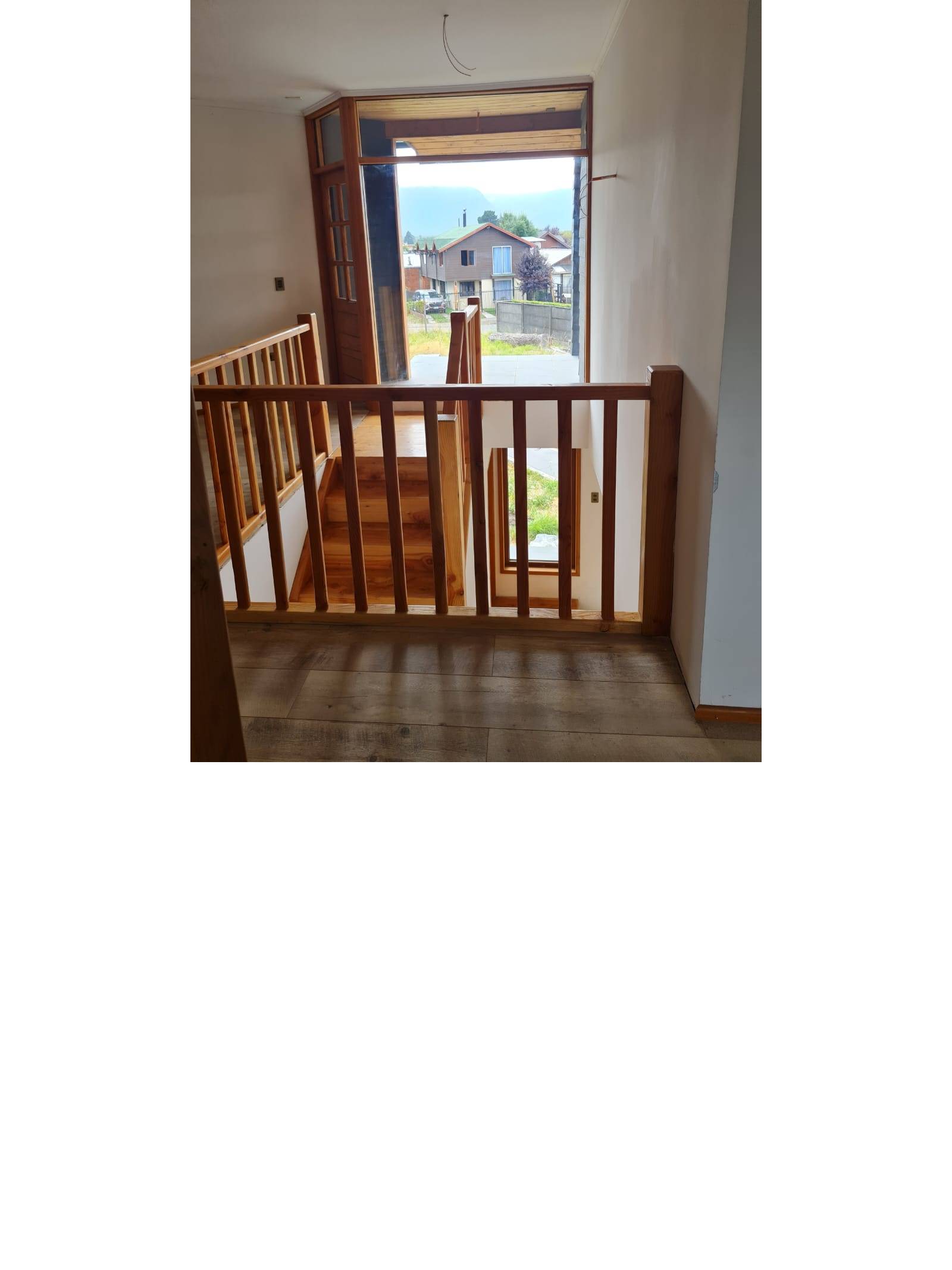 Escalera de madera y ventanal con vista panorámica exterior.