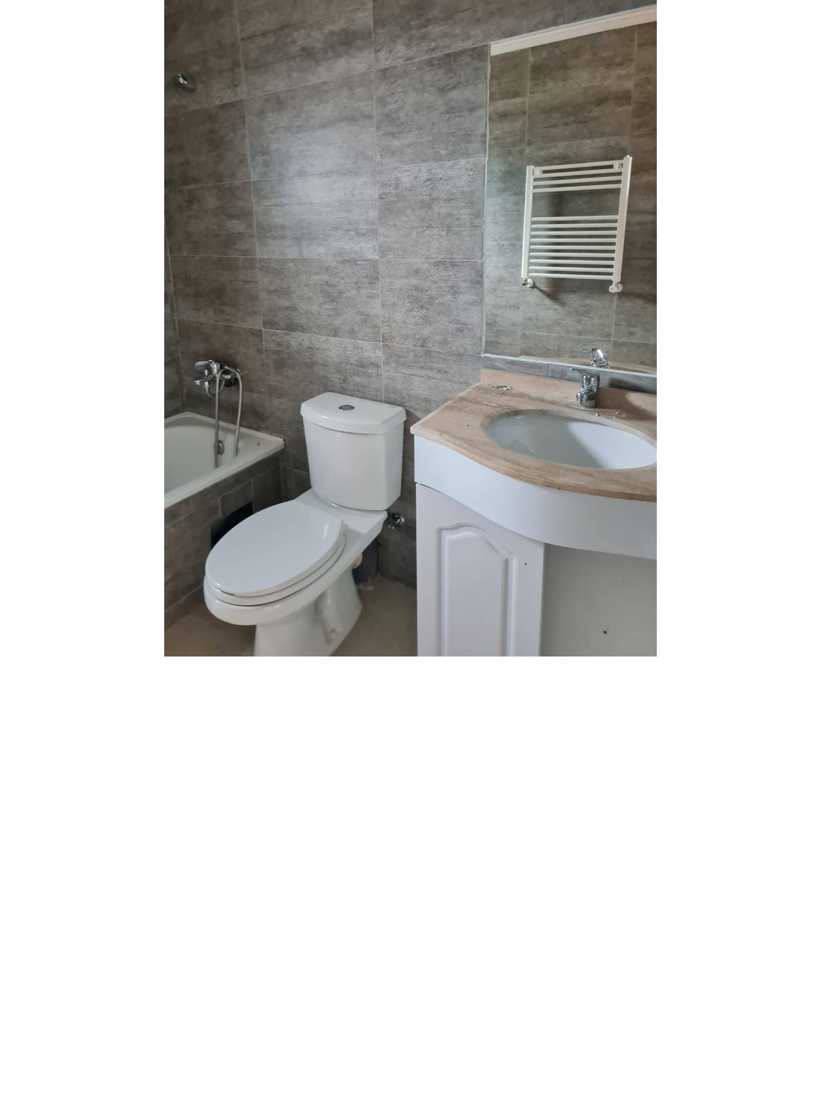 Baño completo con tina, inodoro y lavamanos con espejo.