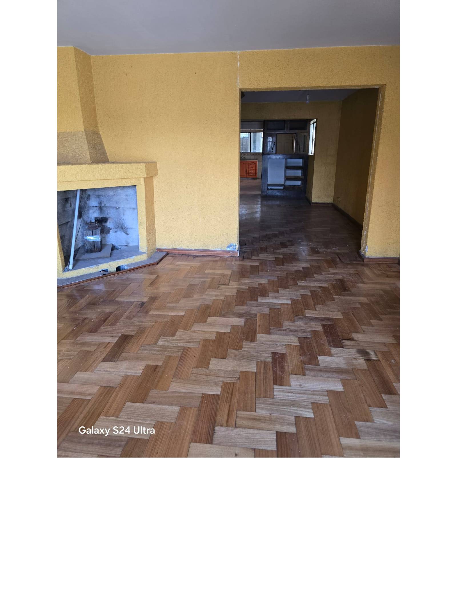 Living amplio con piso de parquet en espiga y chimenea empotrada.