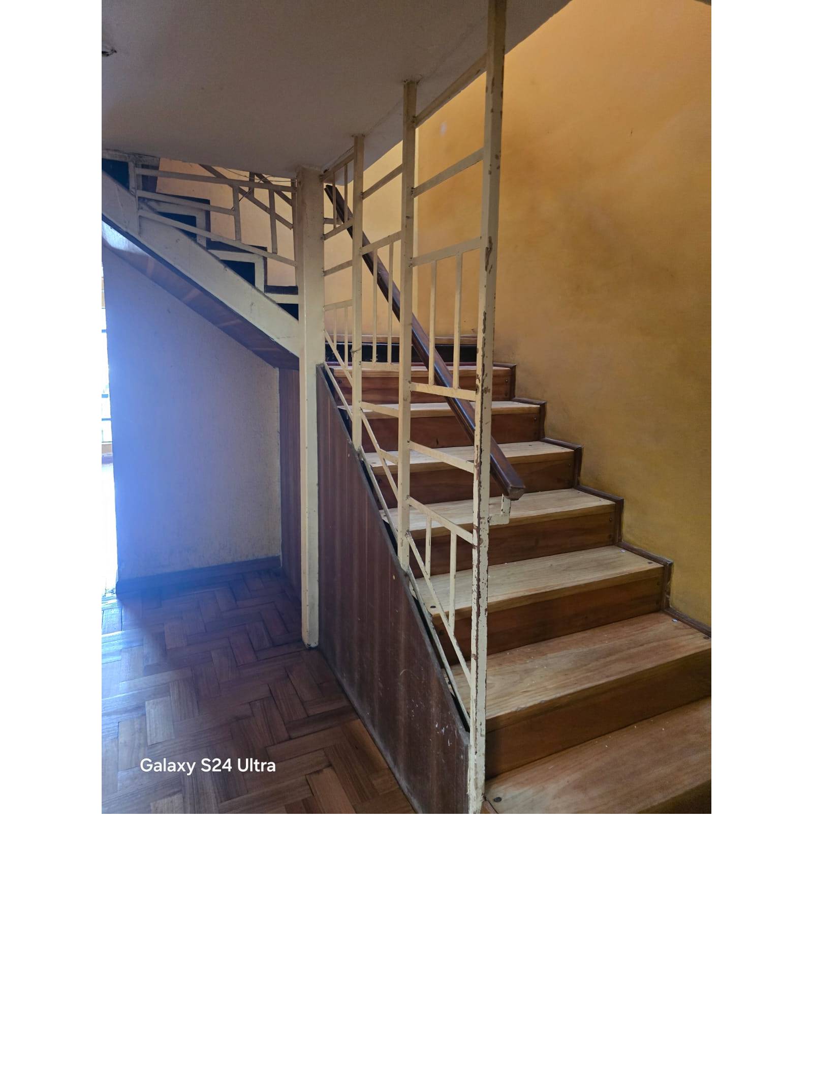 Escalera interior de madera con barandas metálicas.