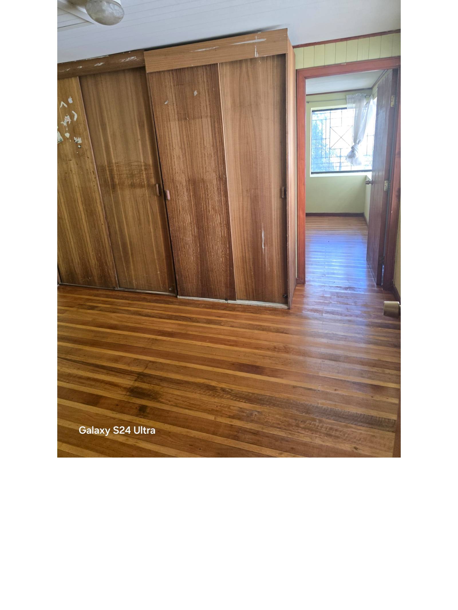 Dormitorio con clóset de madera y vista a habitación contigua.