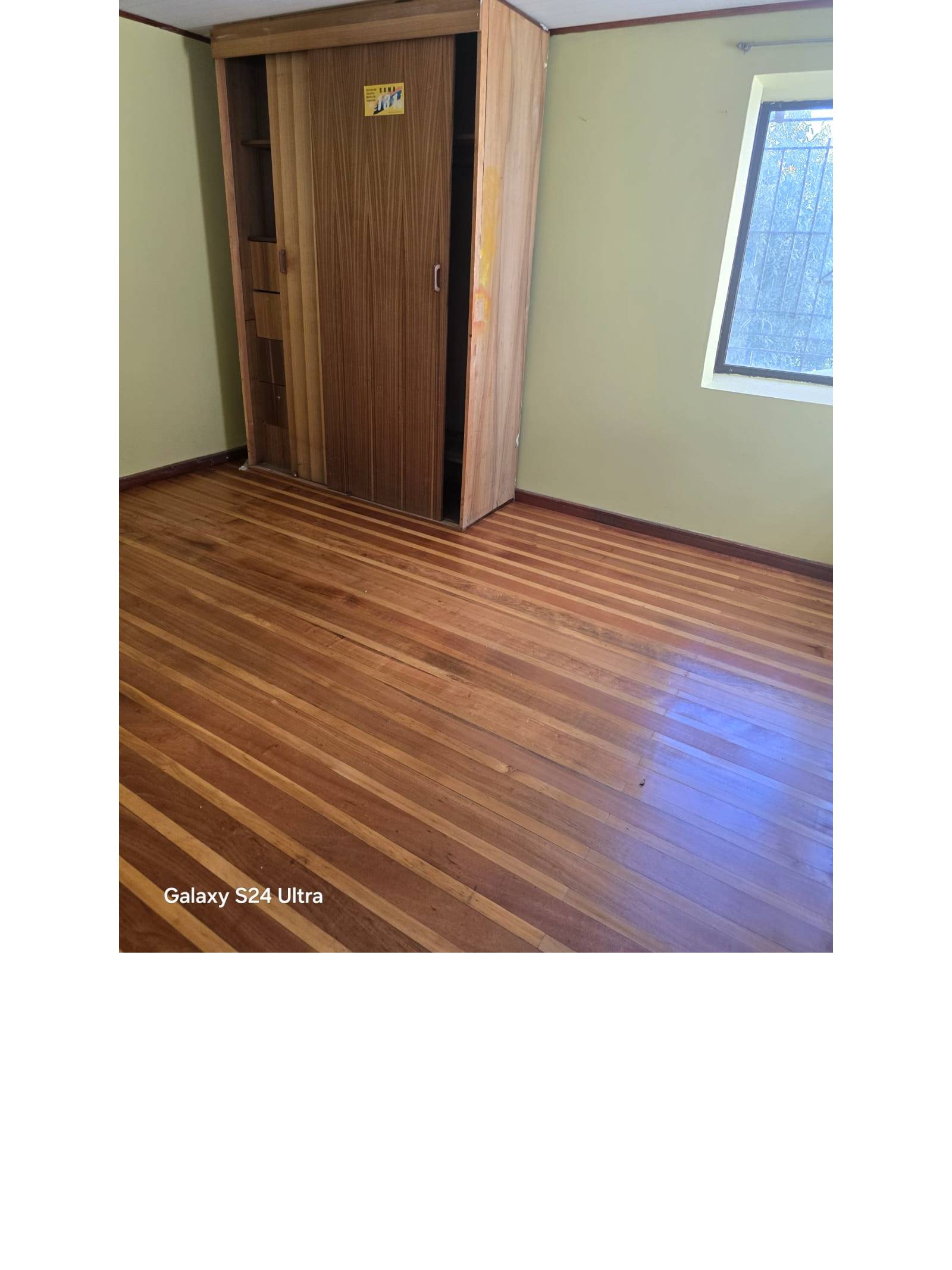 Dormitorio luminoso con clóset de corredera y piso de madera pulido.