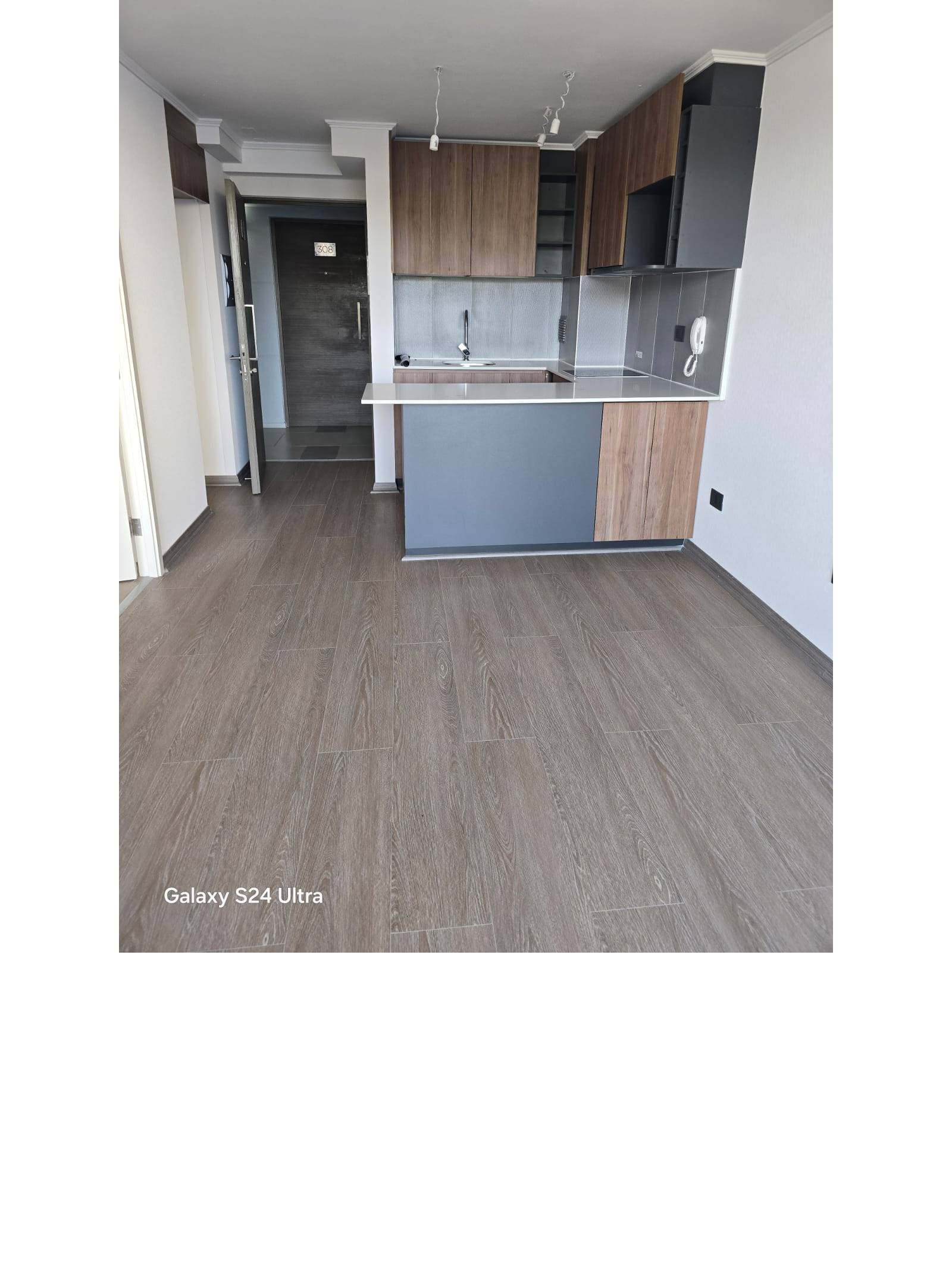 Cocina integrada con mesón desayunador y muebles de madera.