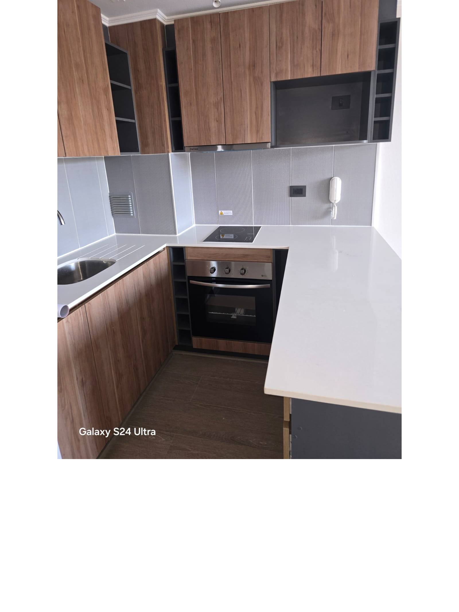 Cocina equipada con encimera vitrocerámica, horno y campana.
