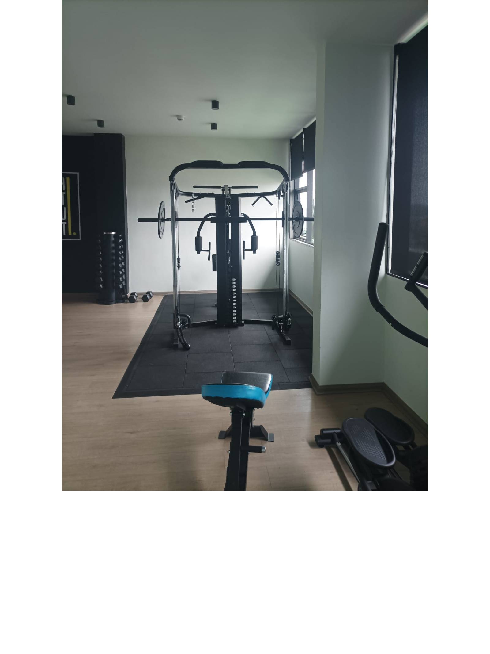 Área de musculación con estación multi fuerza en gimnasio.
