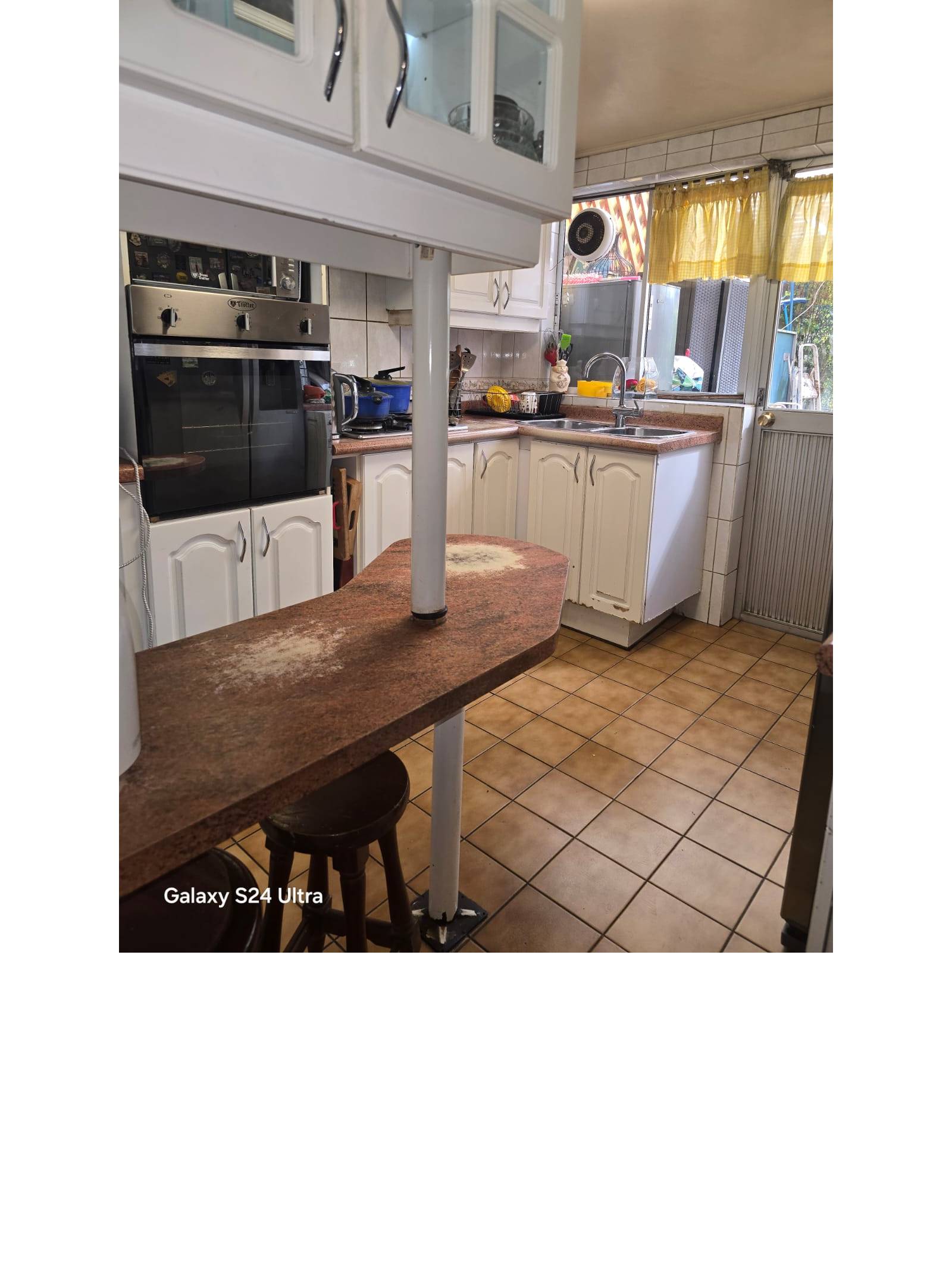 Cocina equipada con muebles blancos y desayunador