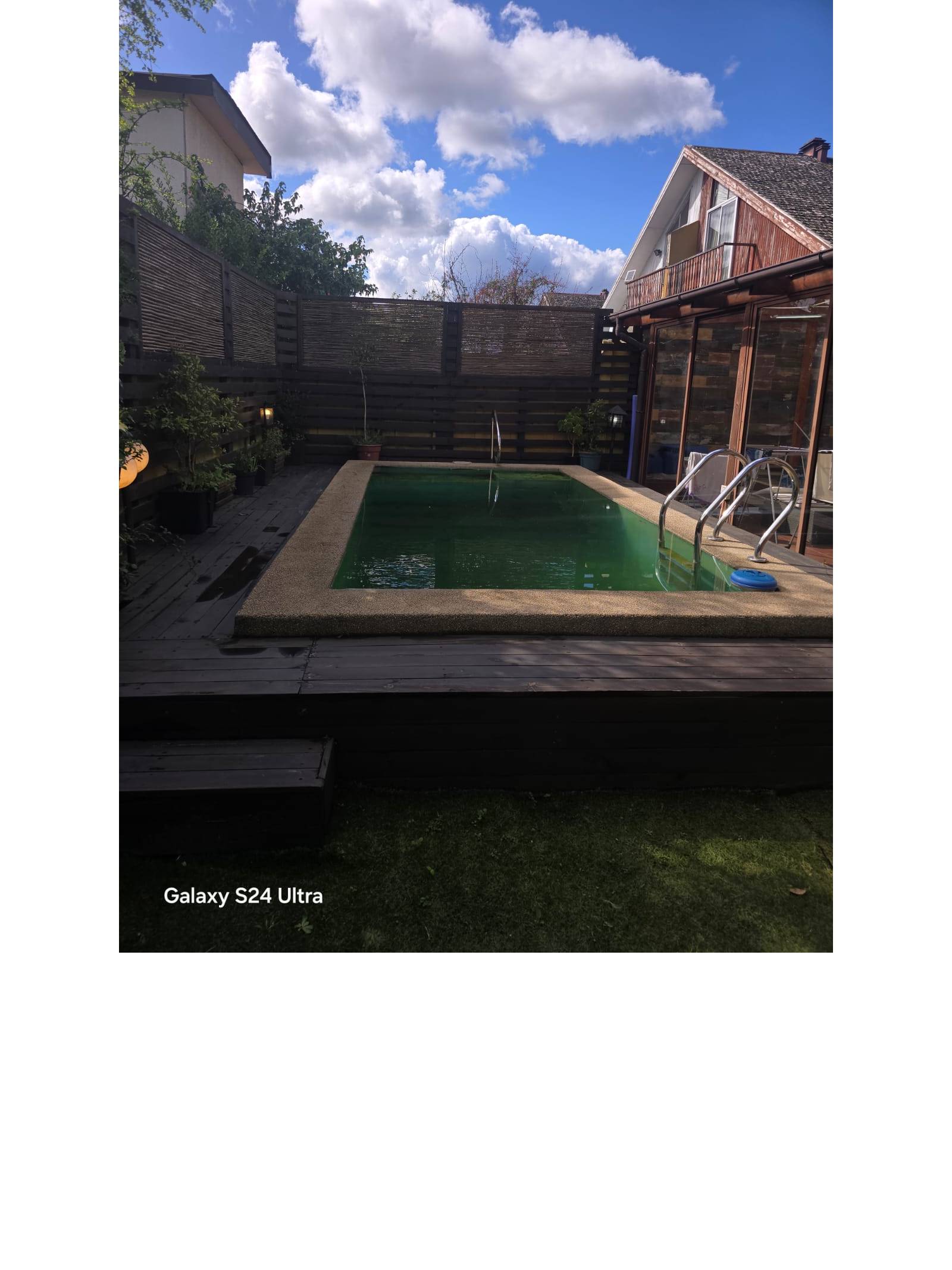Piscina en patio trasero con deck de madera